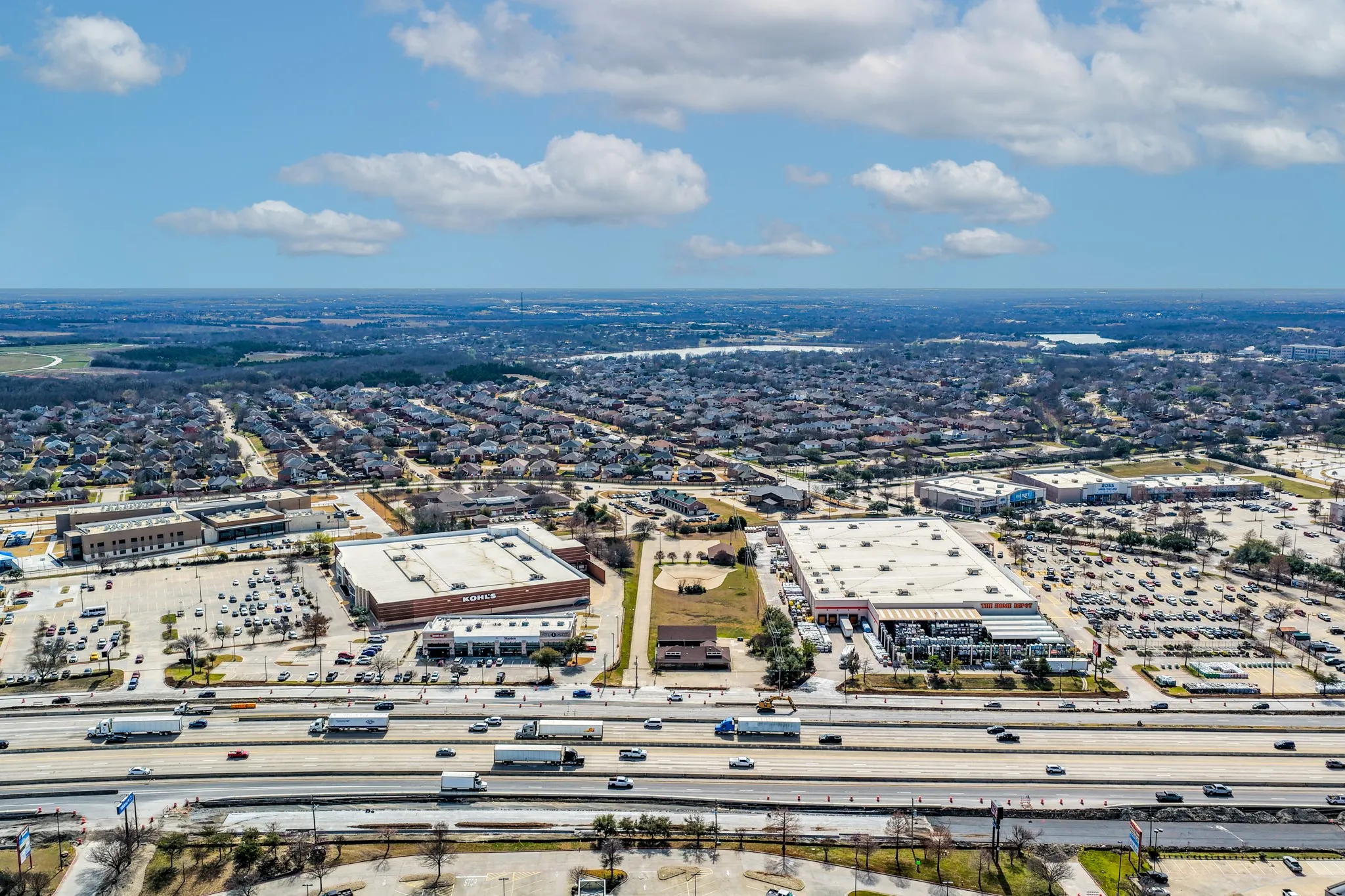 Drone / aerial view of a major roadway, property, and surrounding commercial businesses and area
