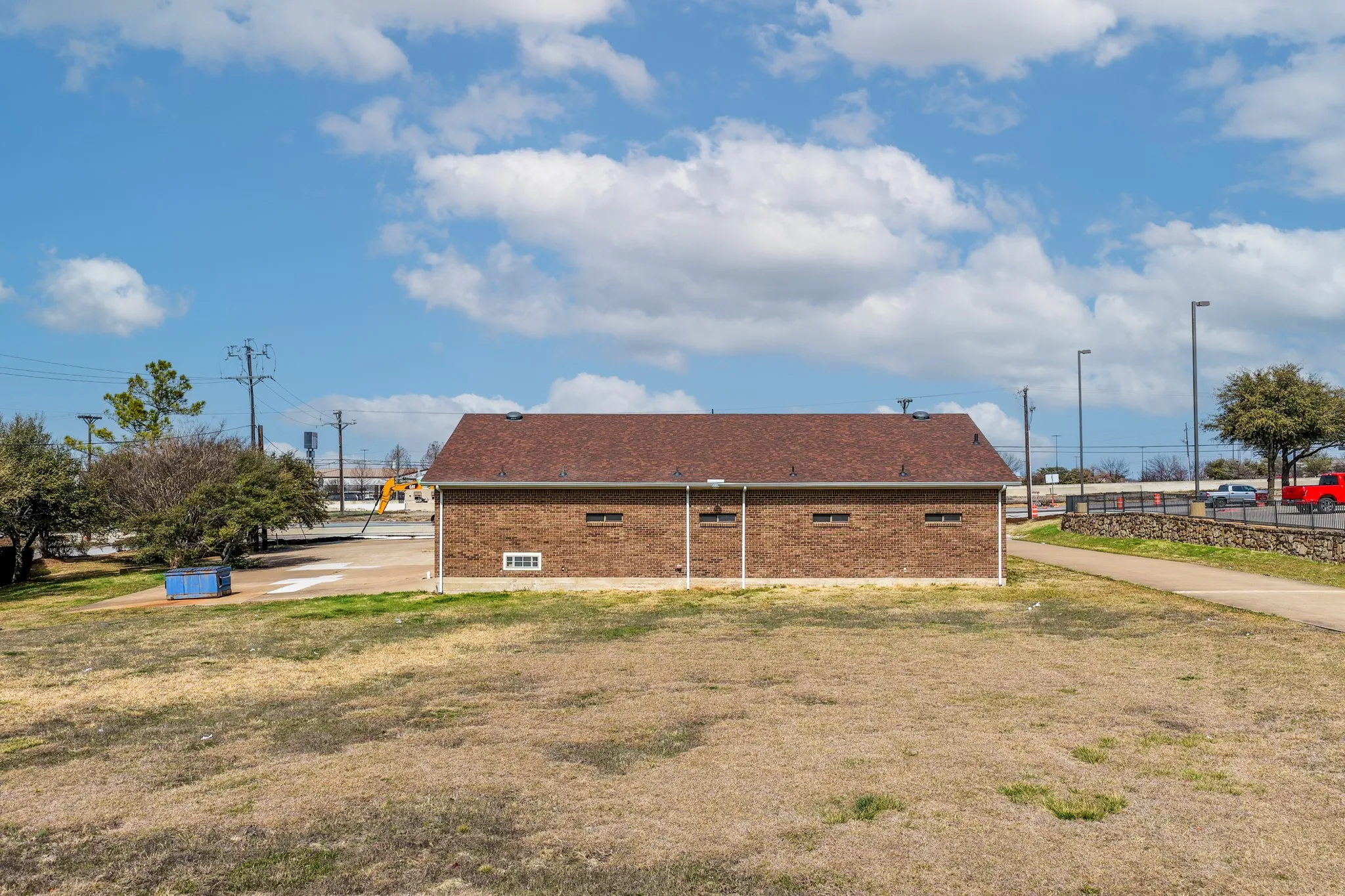 View of side of structure with brick siding, a lawn, and a shingled roof