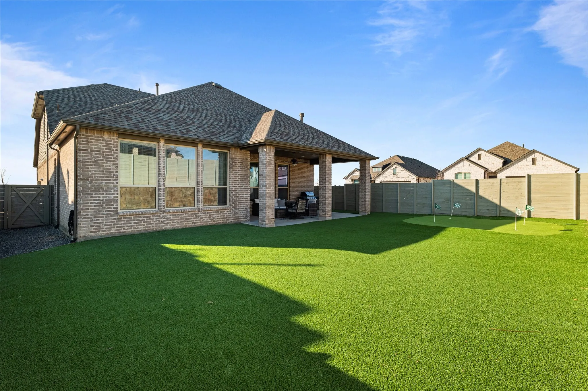 Back of house with brick siding, a patio, roof with shingles, and a fenced backyard