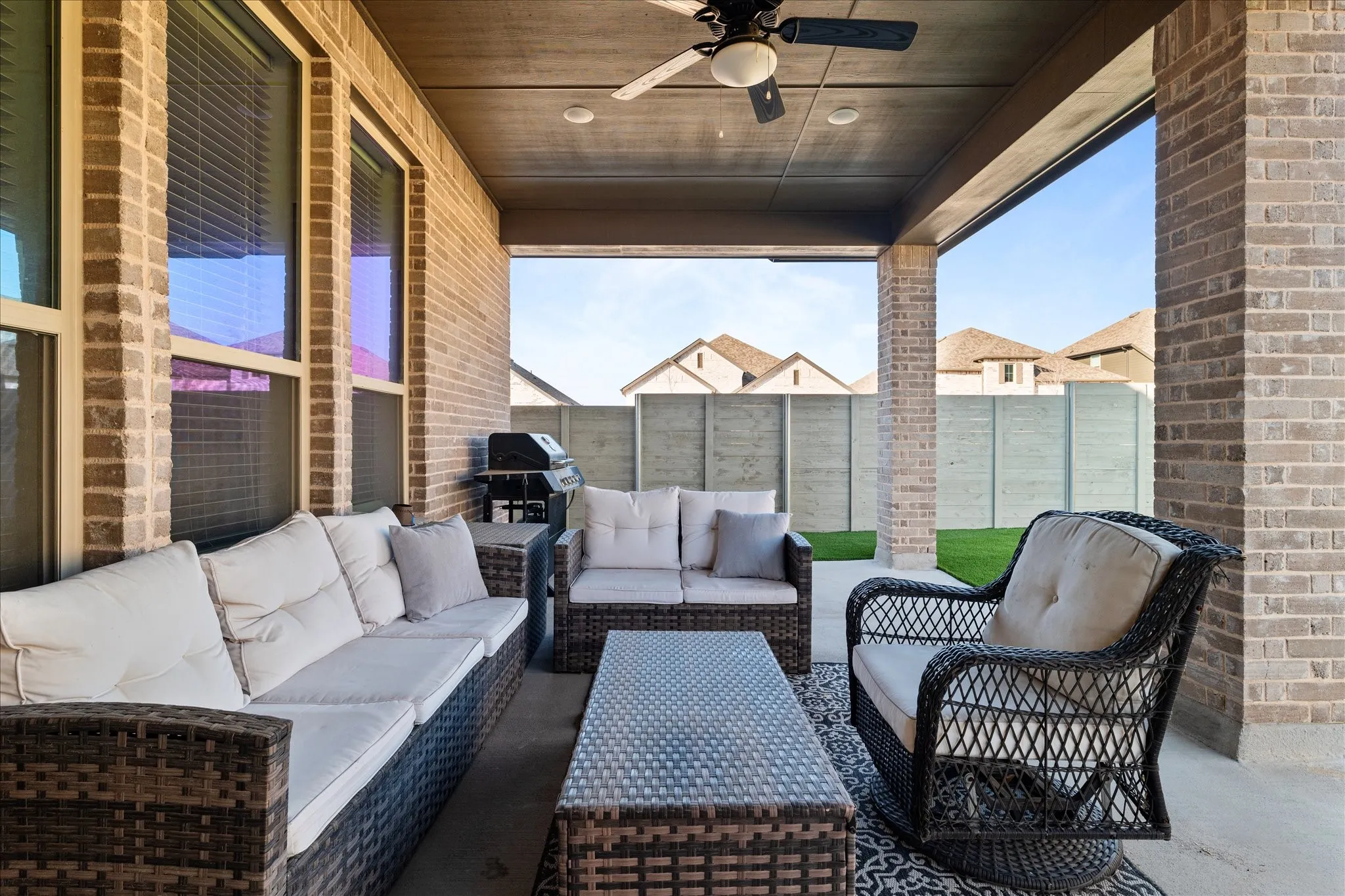 Fenced backyard with ceiling fan, a patio area, a grill, and an outdoor lounge area