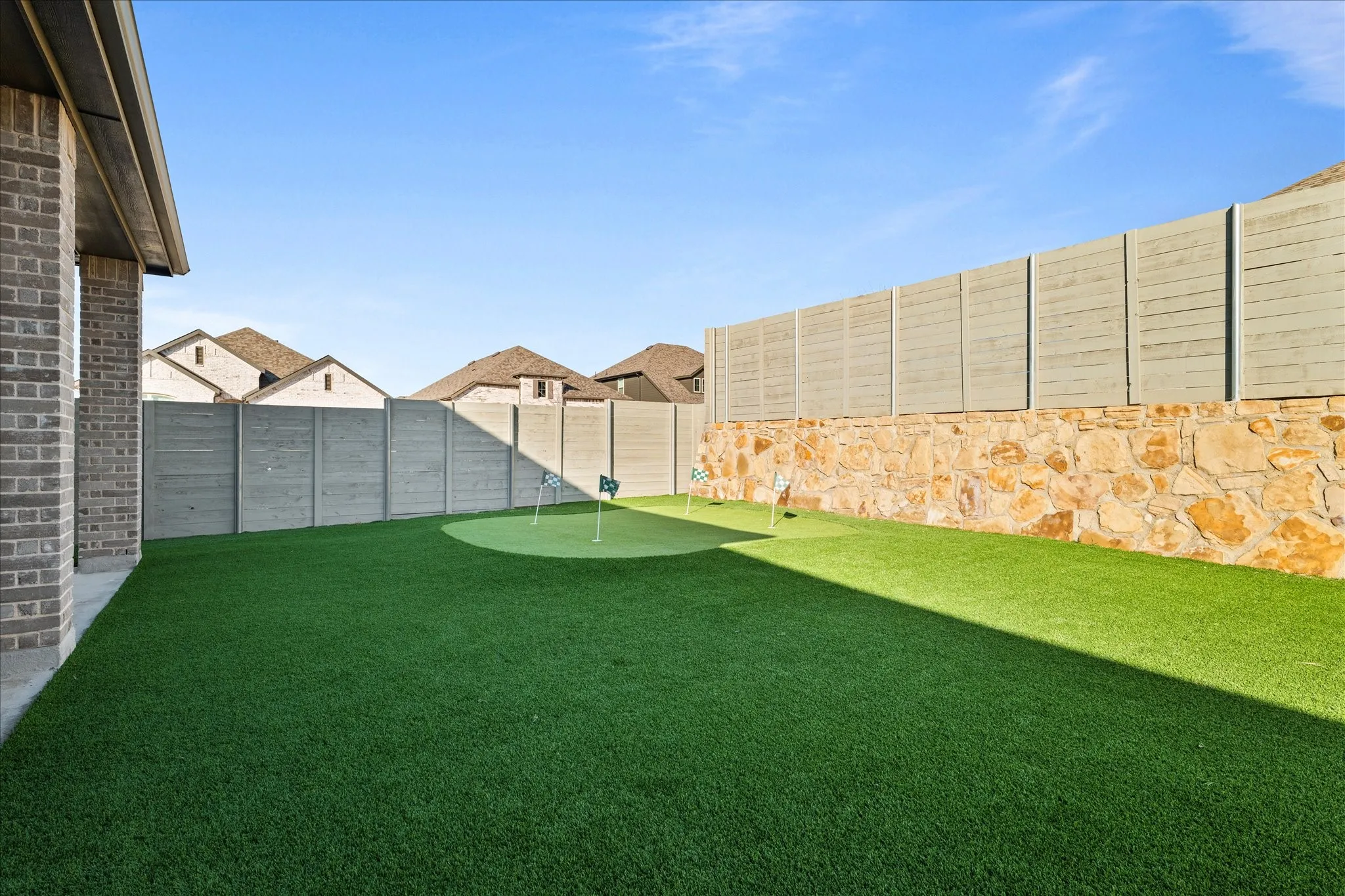 Fenced backyard with a putting area