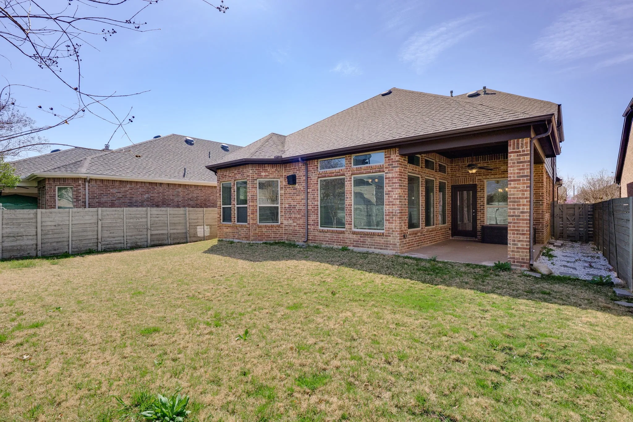 Back of property with brick siding, a fenced backyard, a shingled roof, and a​​‌​​​​‌​​‌‌​‌‌​​​‌‌​‌​‌​‌​​​‌​​ patio