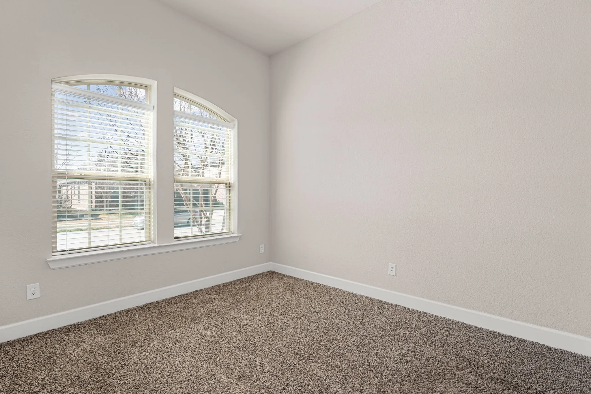 Spare room featuring dark carpet and baseboards