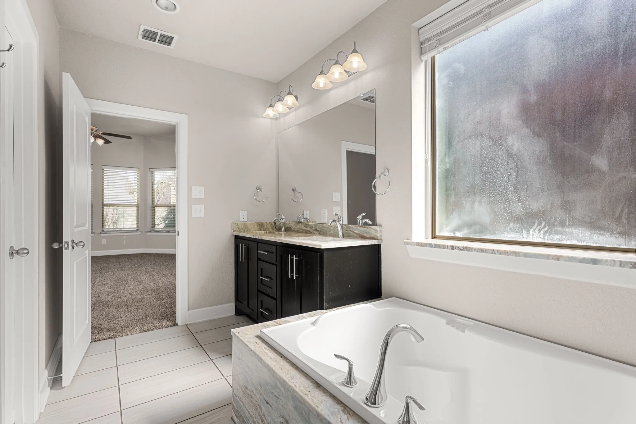Bathroom featuring double vanity, light tile patterned flooring, a garden tub, and ceiling fan