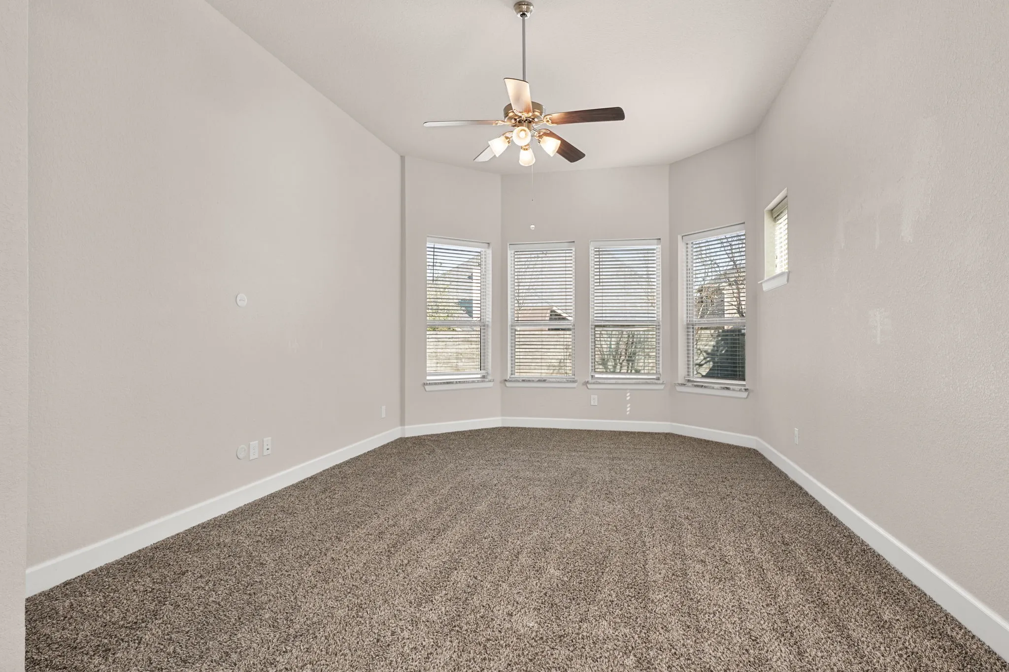 Empty room with dark colored carpet and a ceiling fan