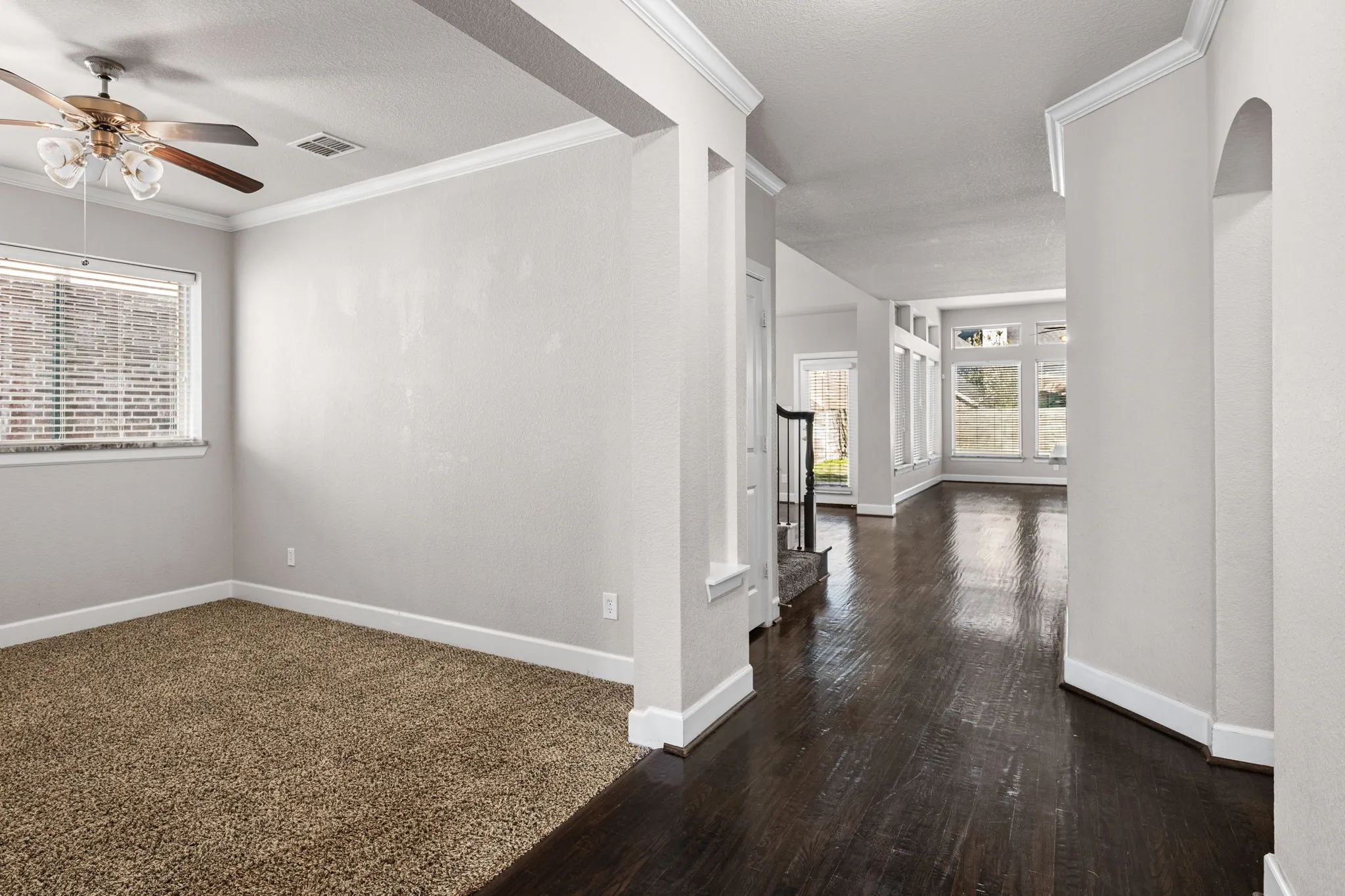 Corridor with crown molding, a textured ceiling, and dark wood-style floors