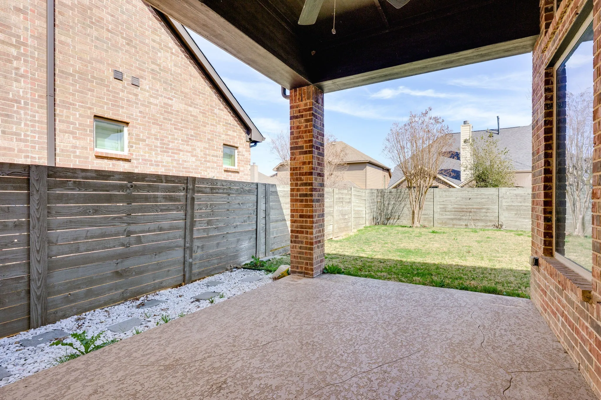 Fenced backyard with a patio area and a ceiling fan