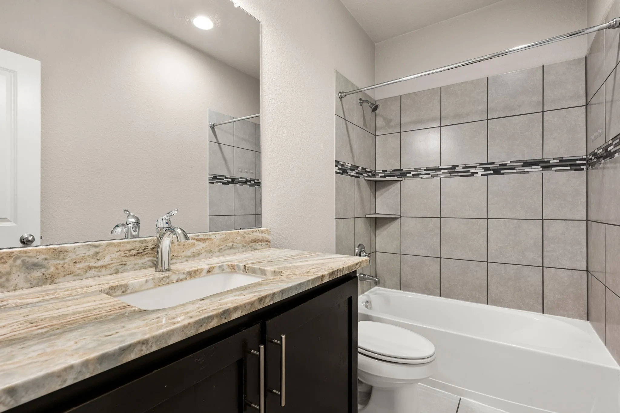 Full bath featuring vanity, shower / washtub combination, tile patterned floors, and a textured wall