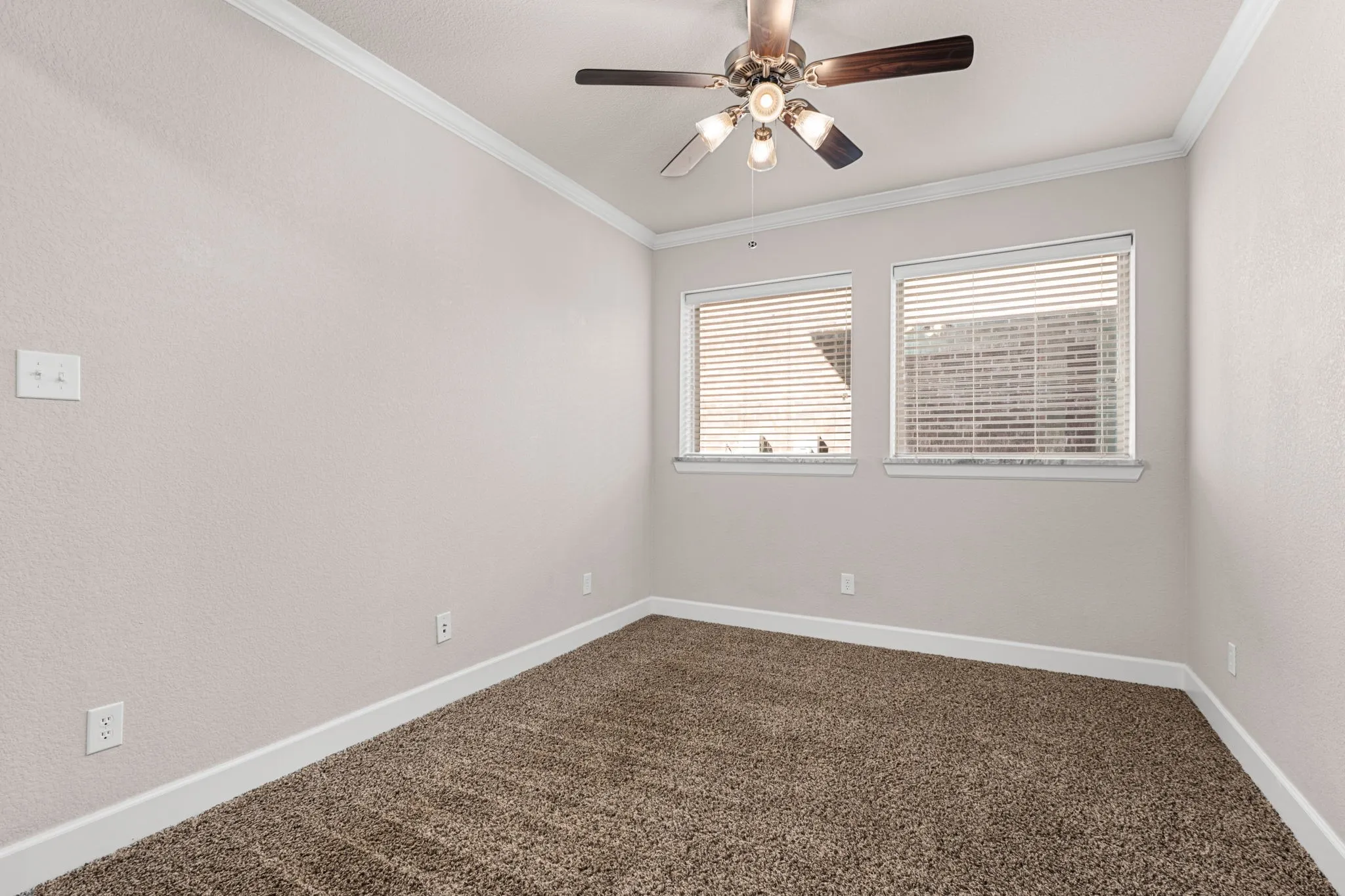 Unfurnished room featuring ceiling fan, dark carpet, healthy amount of natural light, and ornamental molding