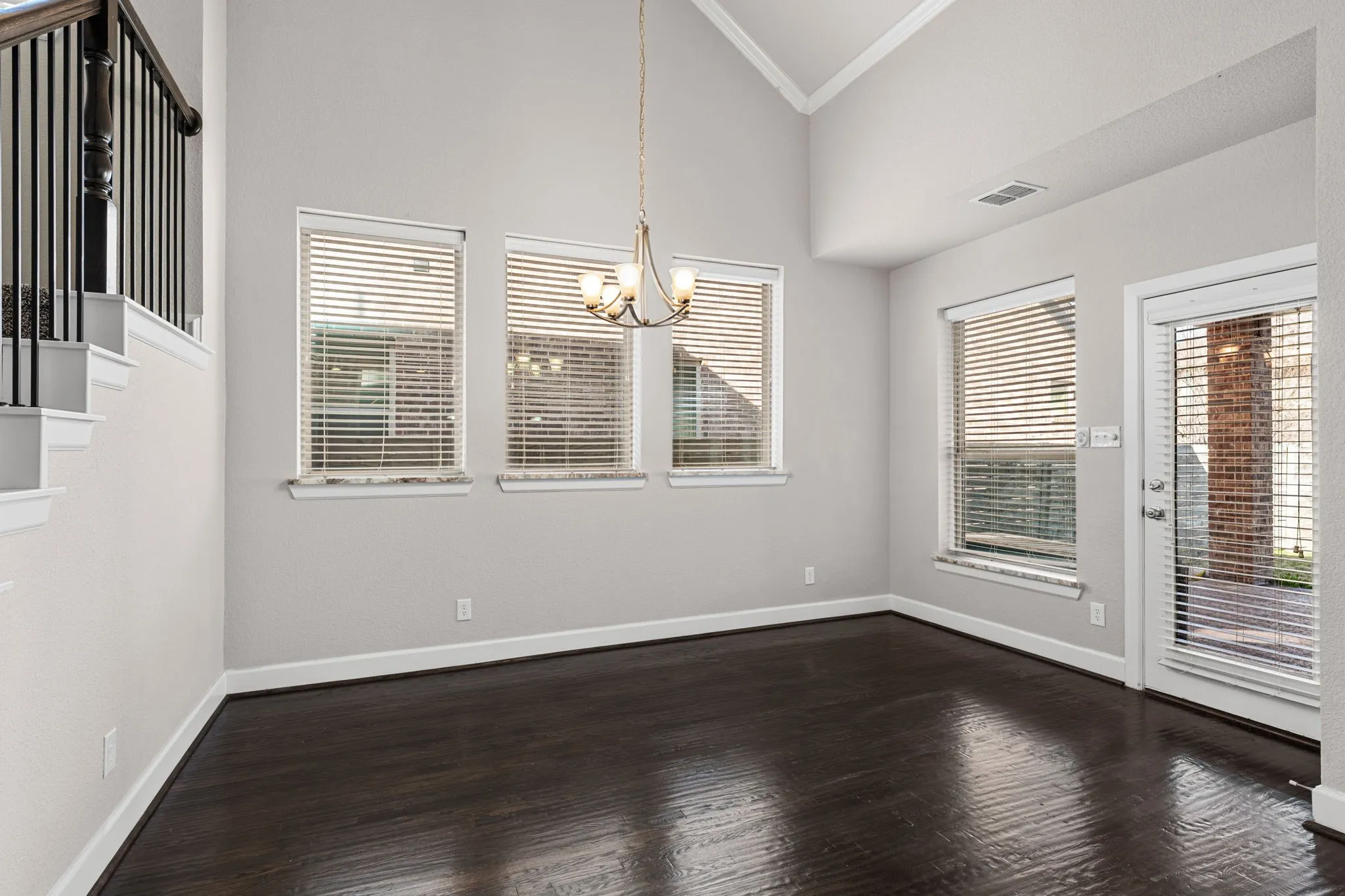 Unfurnished dining area with ornamental molding, lofted ceiling, a chandelier, dark wood-style floors, and plenty of natural light