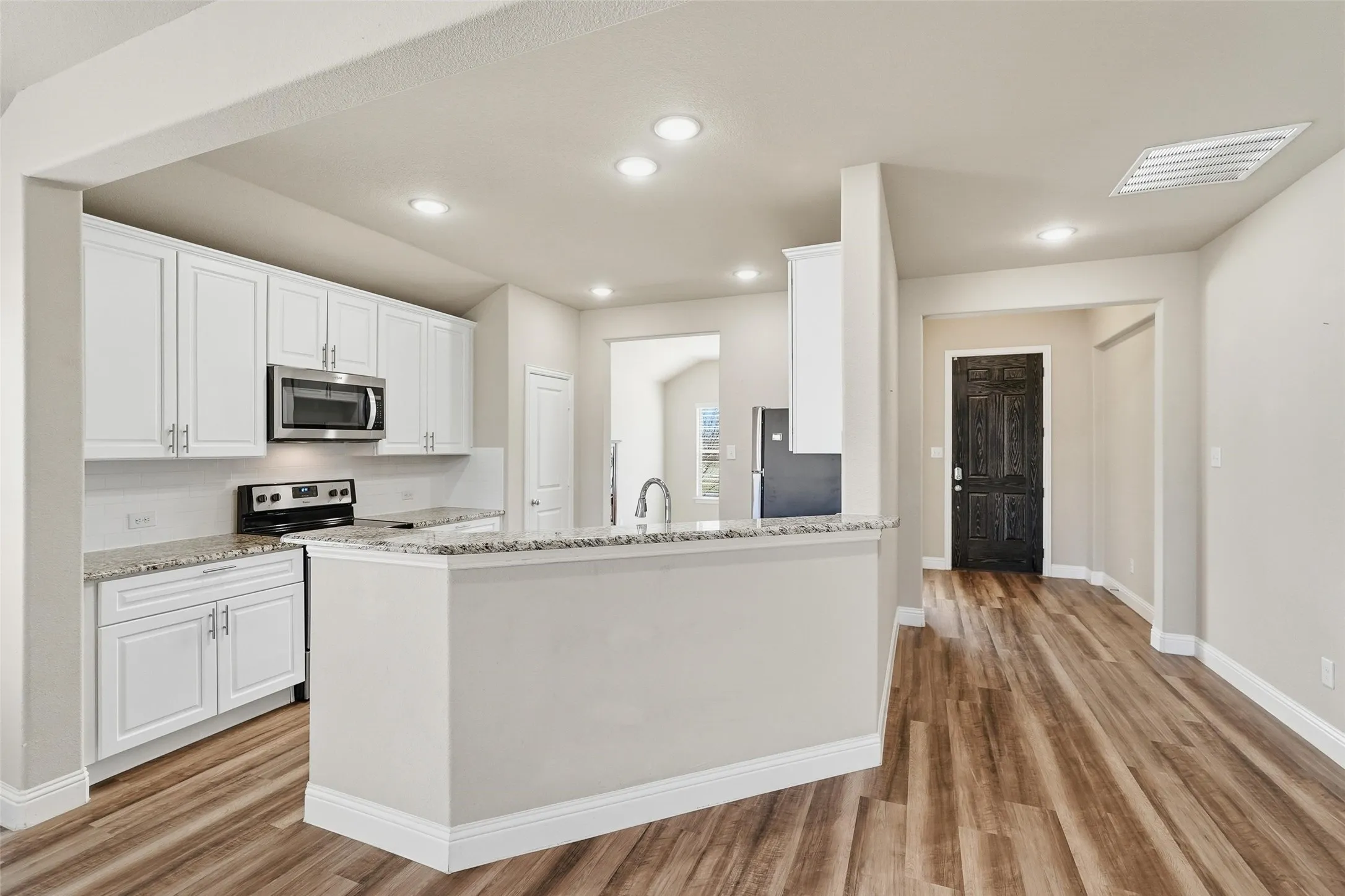 Kitchen with granite counter tops and stainless appliances opens to the large living space.