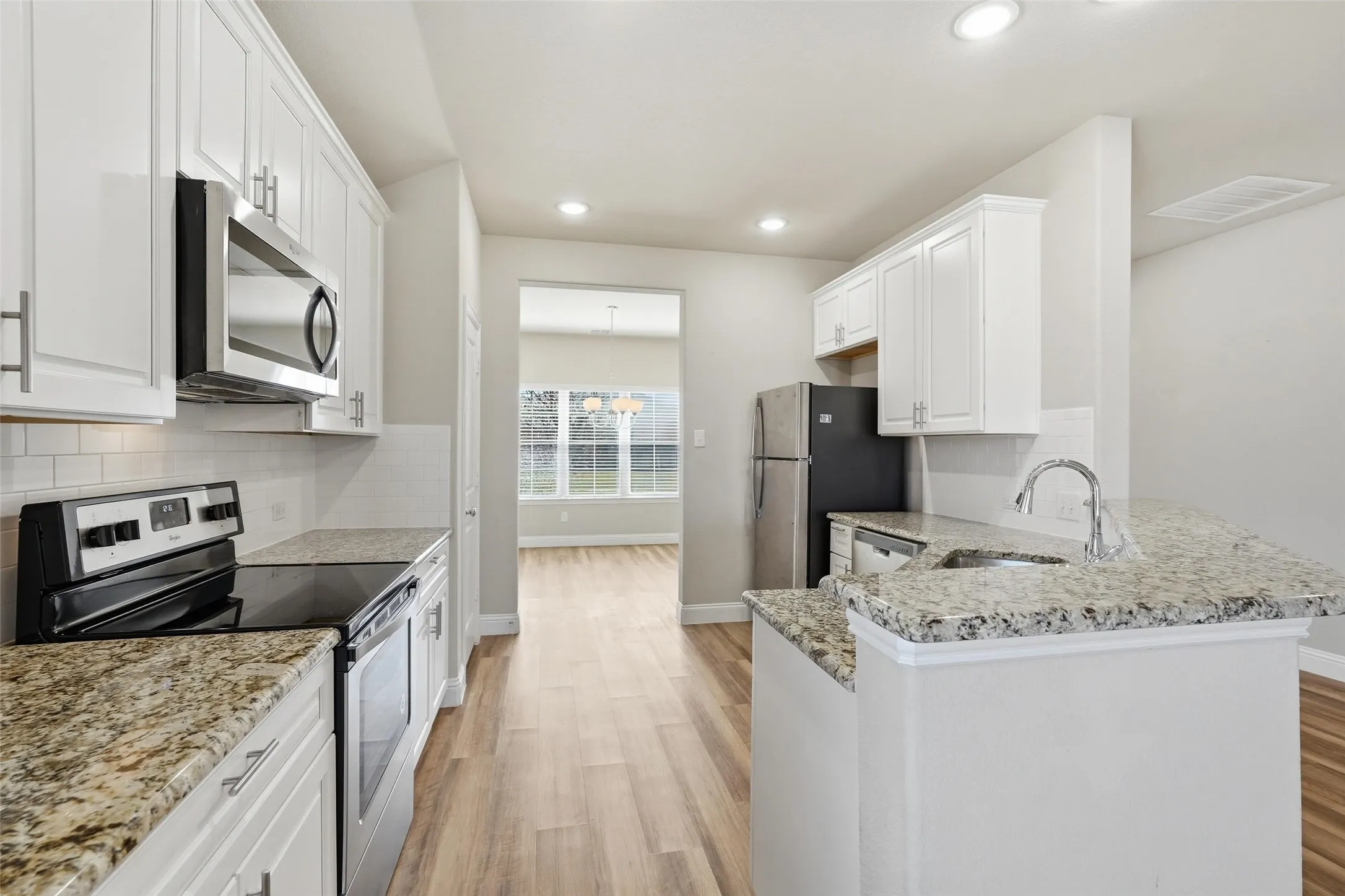 Kitchen with granite counter tops and stainless appliances opens to the large living space.