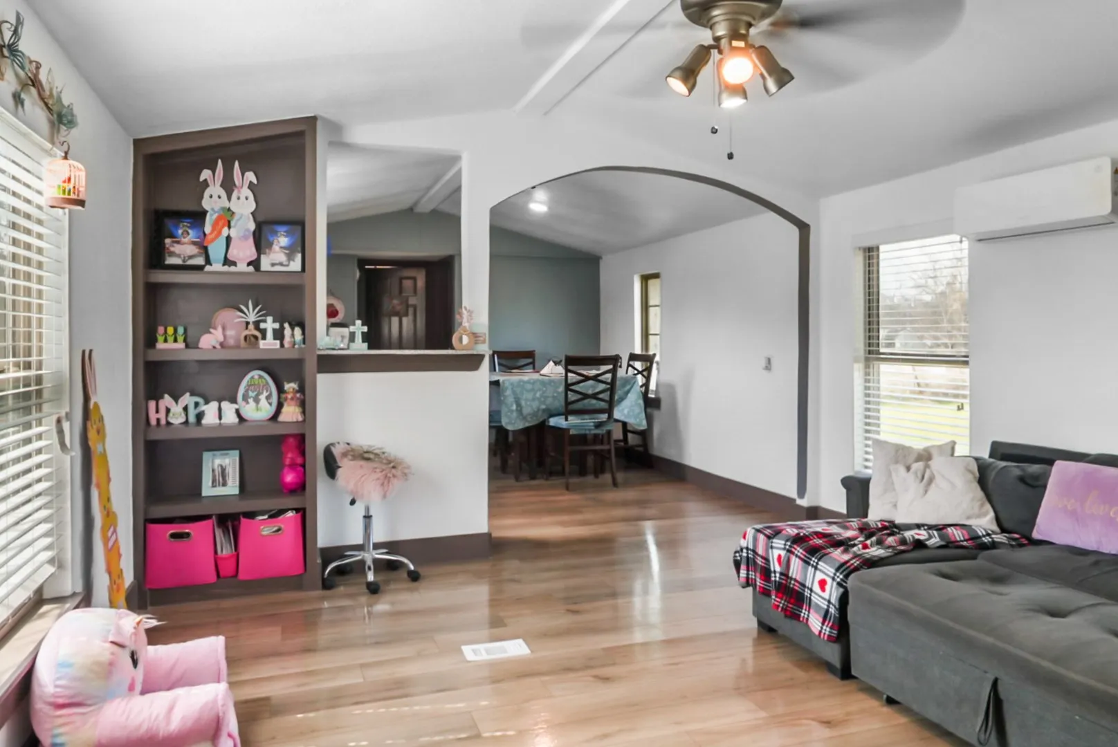 Living area featuring light wood finished floors, a ceiling fan, and arched walkways