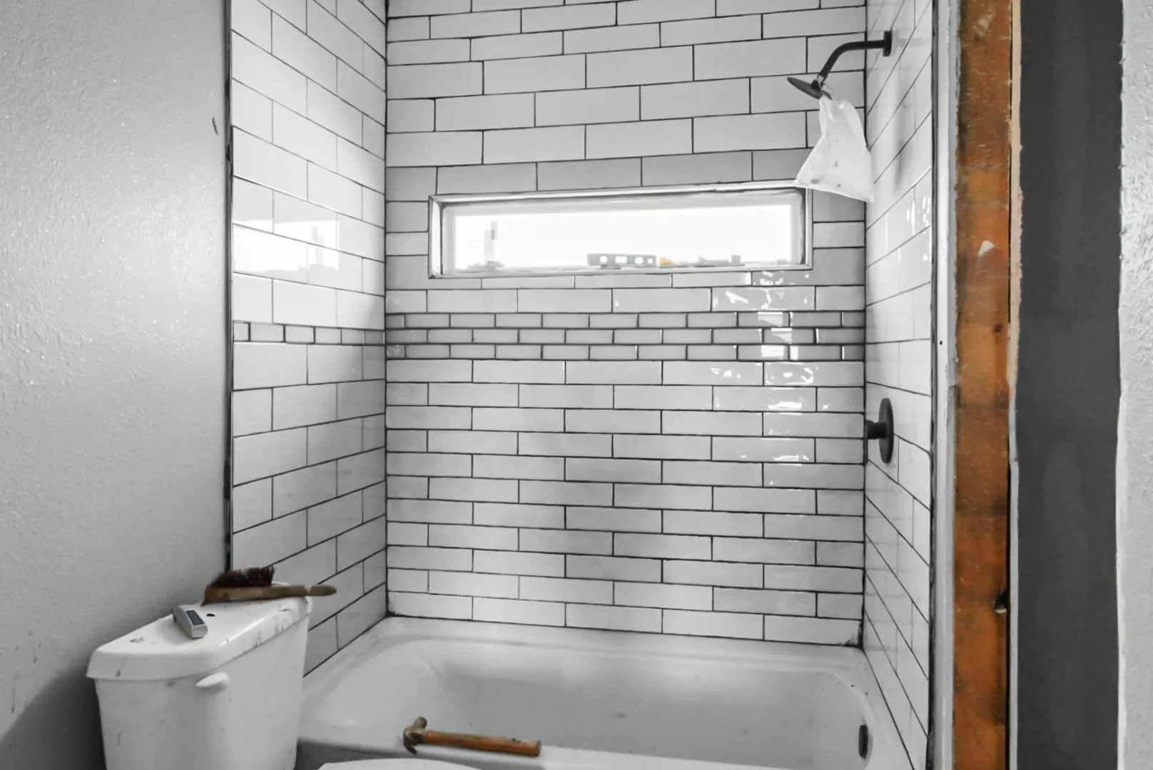 Bathroom featuring a textured wall and  shower combination