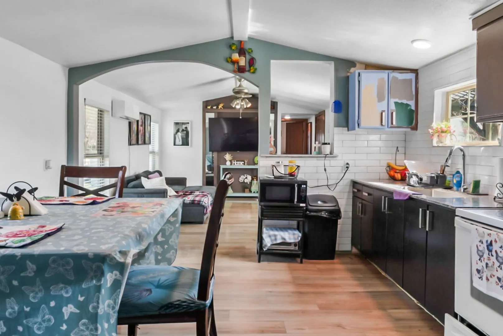 Kitchen featuring healthy amount of natural light, tasteful backsplash, light wood-style flooring, and arched walkways