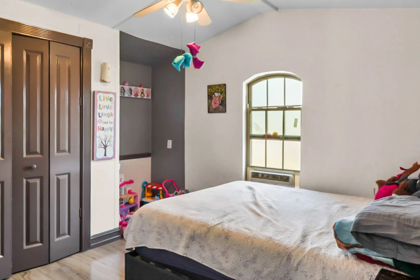 Bedroom with light wood finished floors, lofted ceiling, a ceiling fan, and a closet