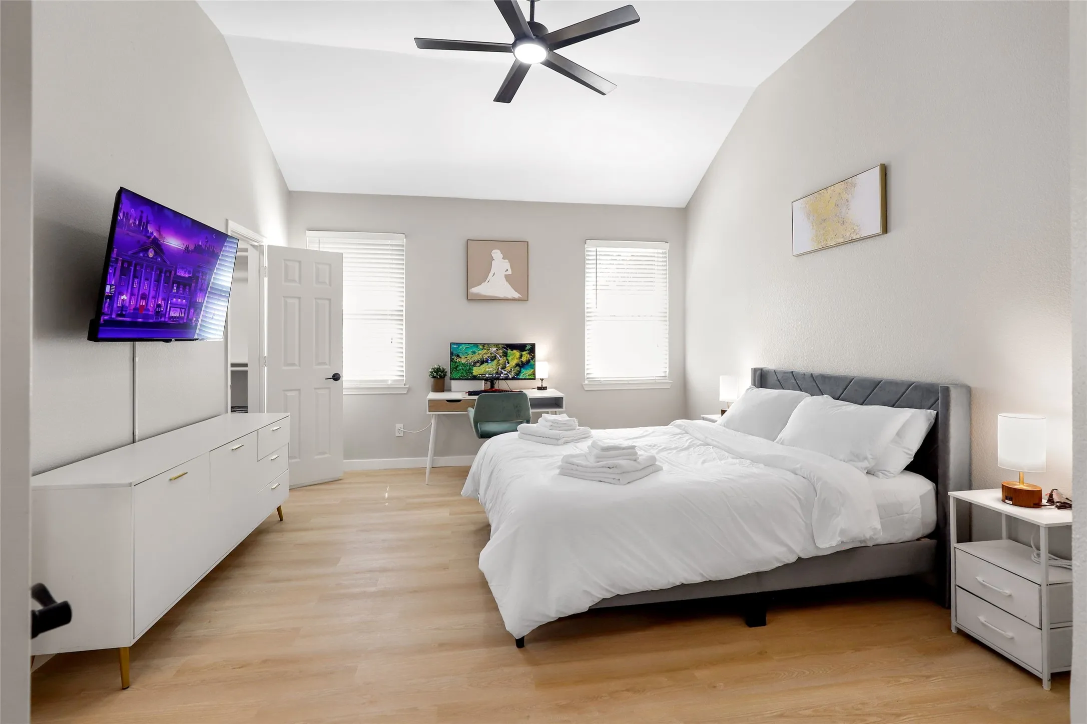 Bedroom with vaulted ceiling, light wood-type flooring, and a ceiling fan