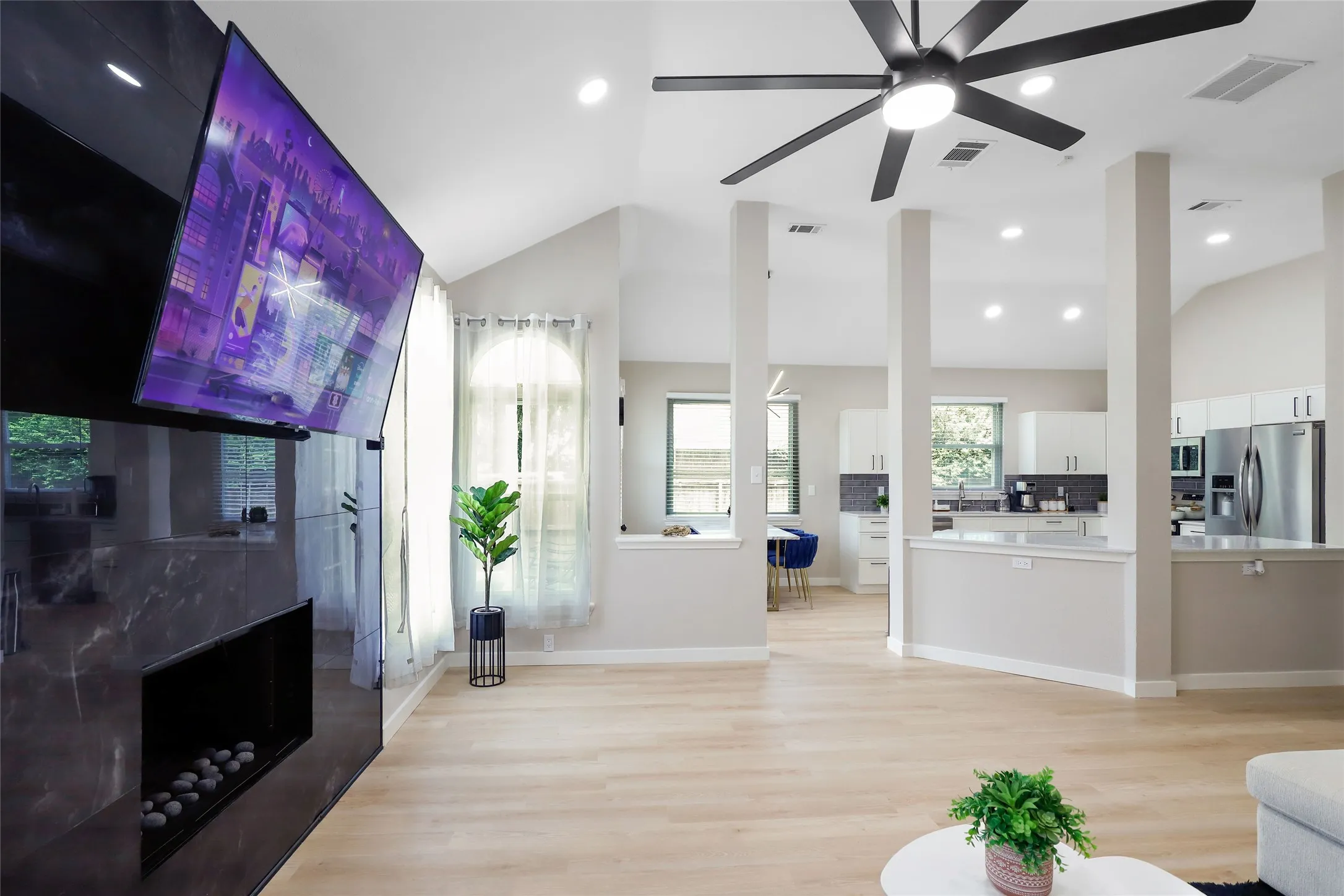 Living area with vaulted ceiling, a ceiling fan, light wood-style flooring, and recessed lighting