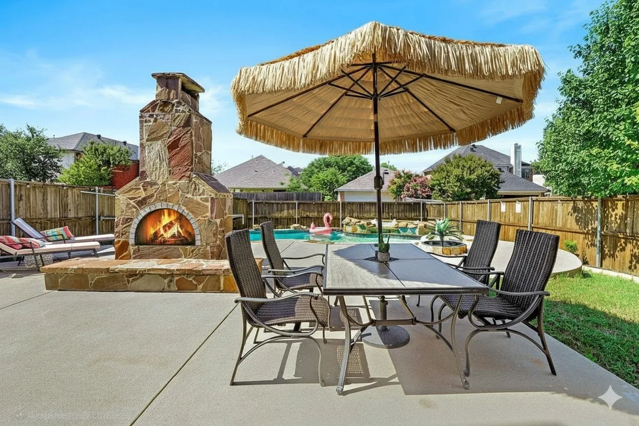 Fenced backyard featuring an outdoor stone fireplace, a patio area, and outdoor dining area