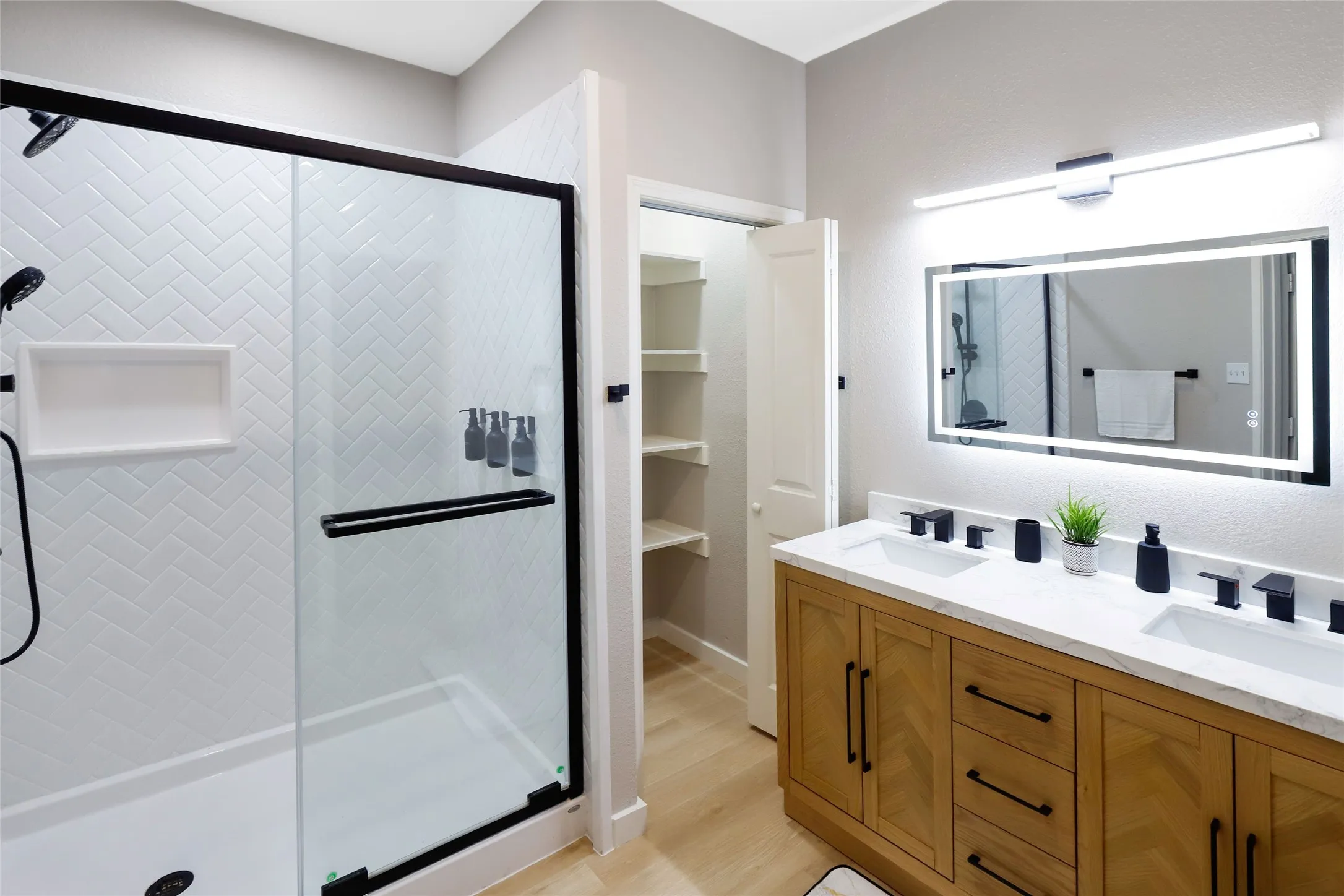 Bathroom with a shower stall, double vanity, and wood finished floors