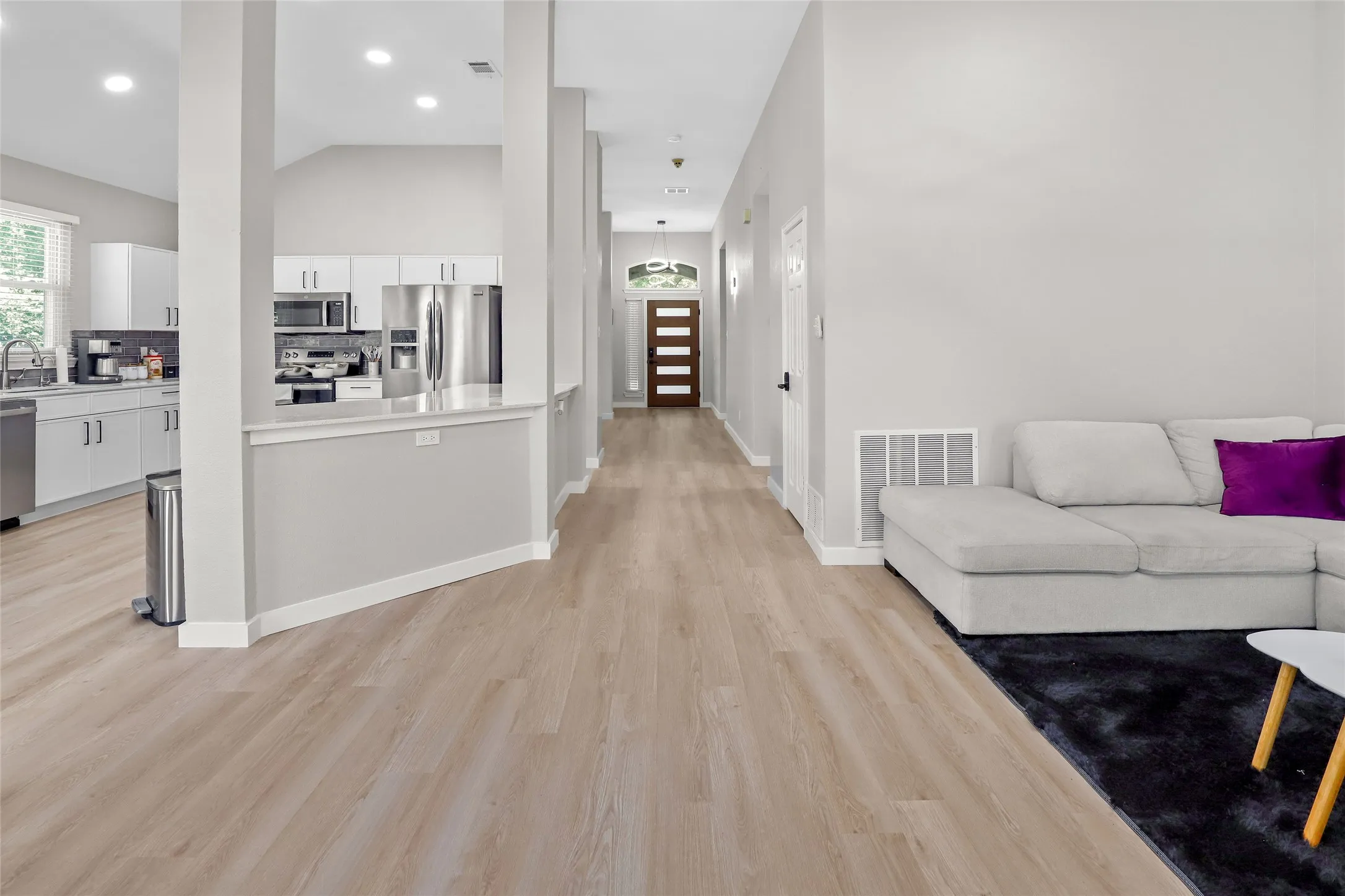 Hallway with light wood-style flooring, recessed lighting, and lofted ceiling
