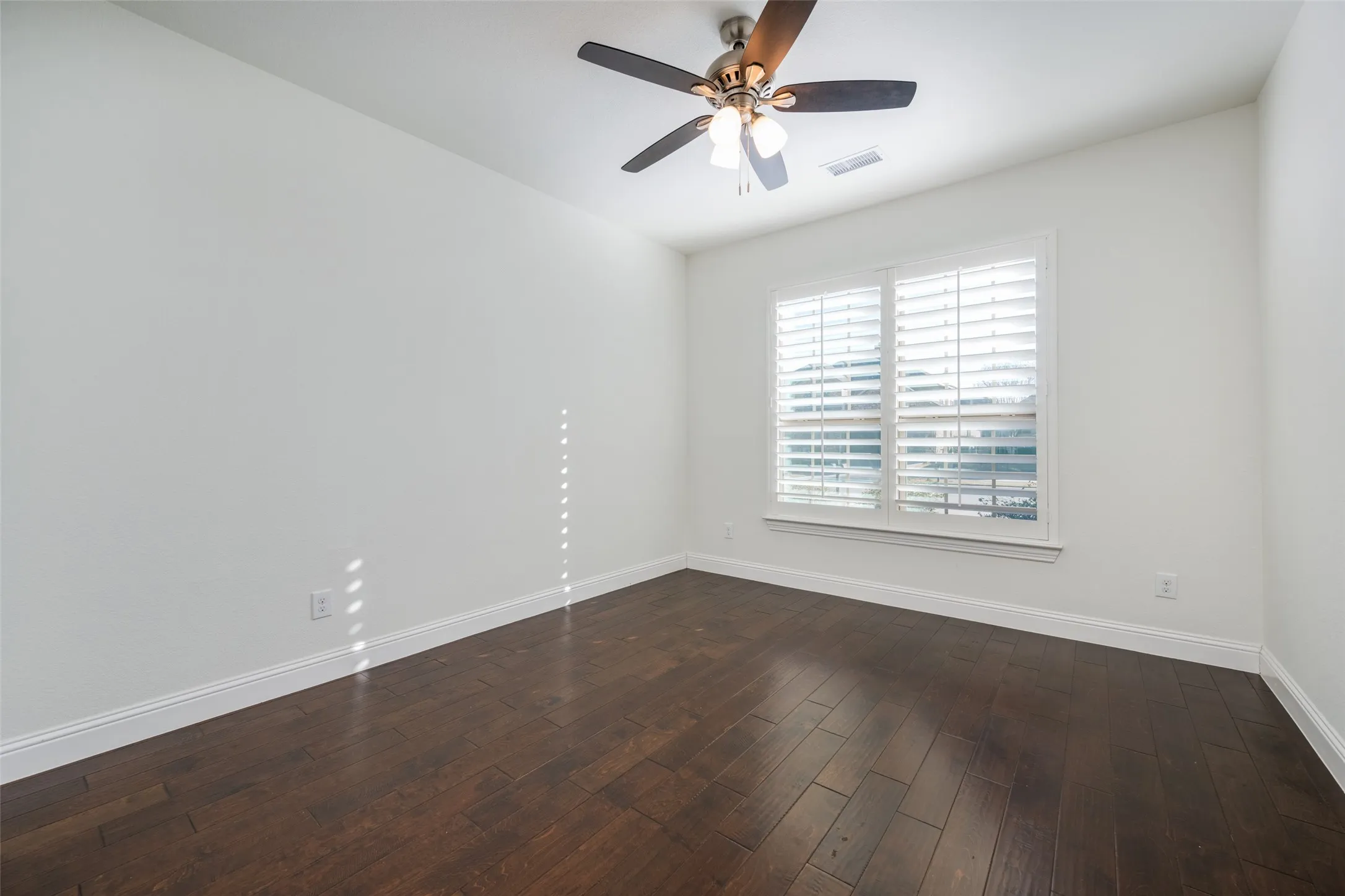 Spare room featuring ceiling fan and dark wood-style flooring