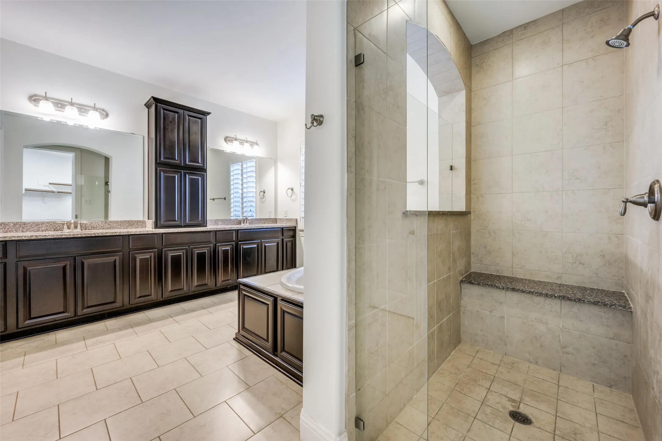 Bathroom with double vanity, a walk in shower, and light tile patterned floors