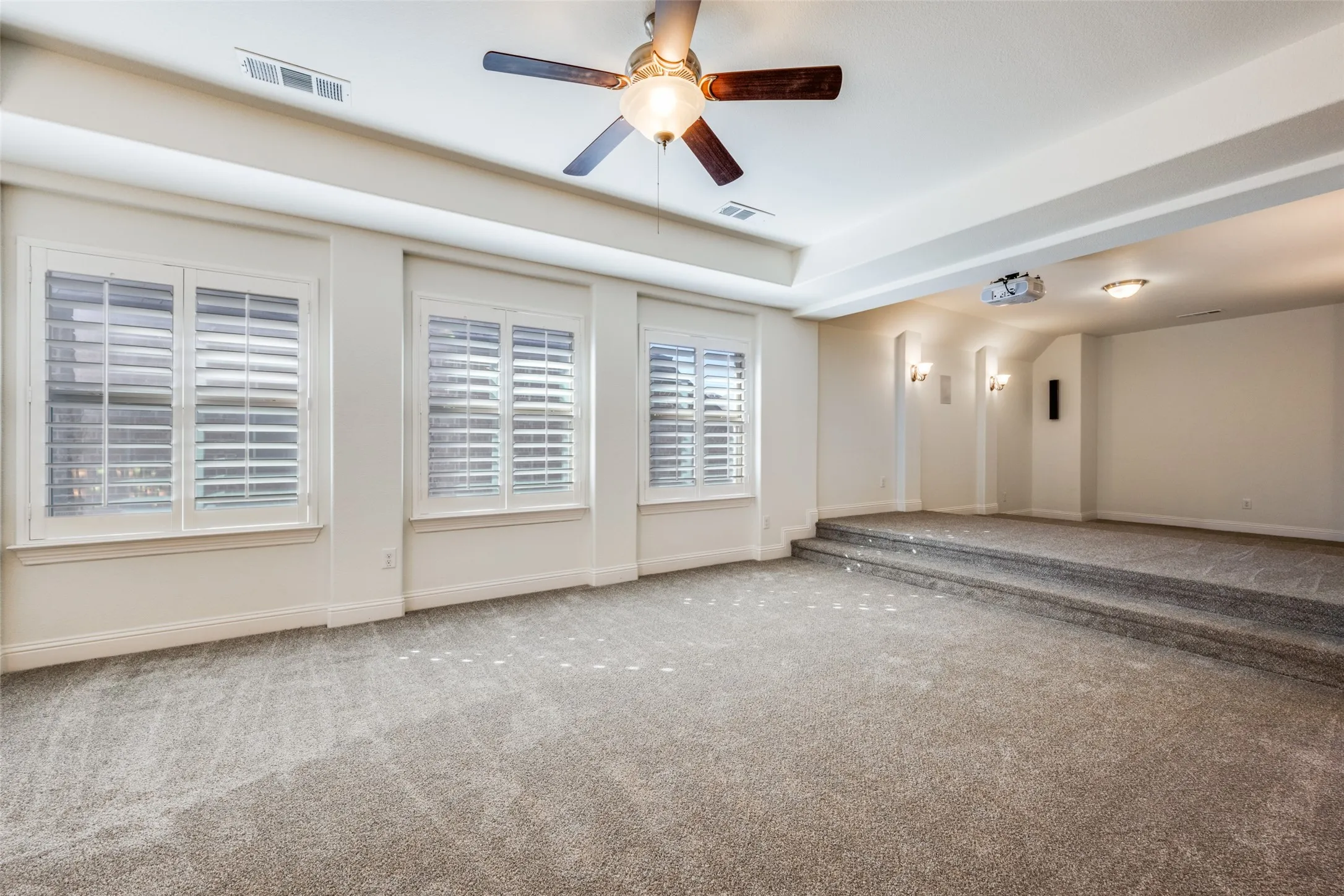 Unfurnished room with carpet floors, ceiling fan, and a raised ceiling