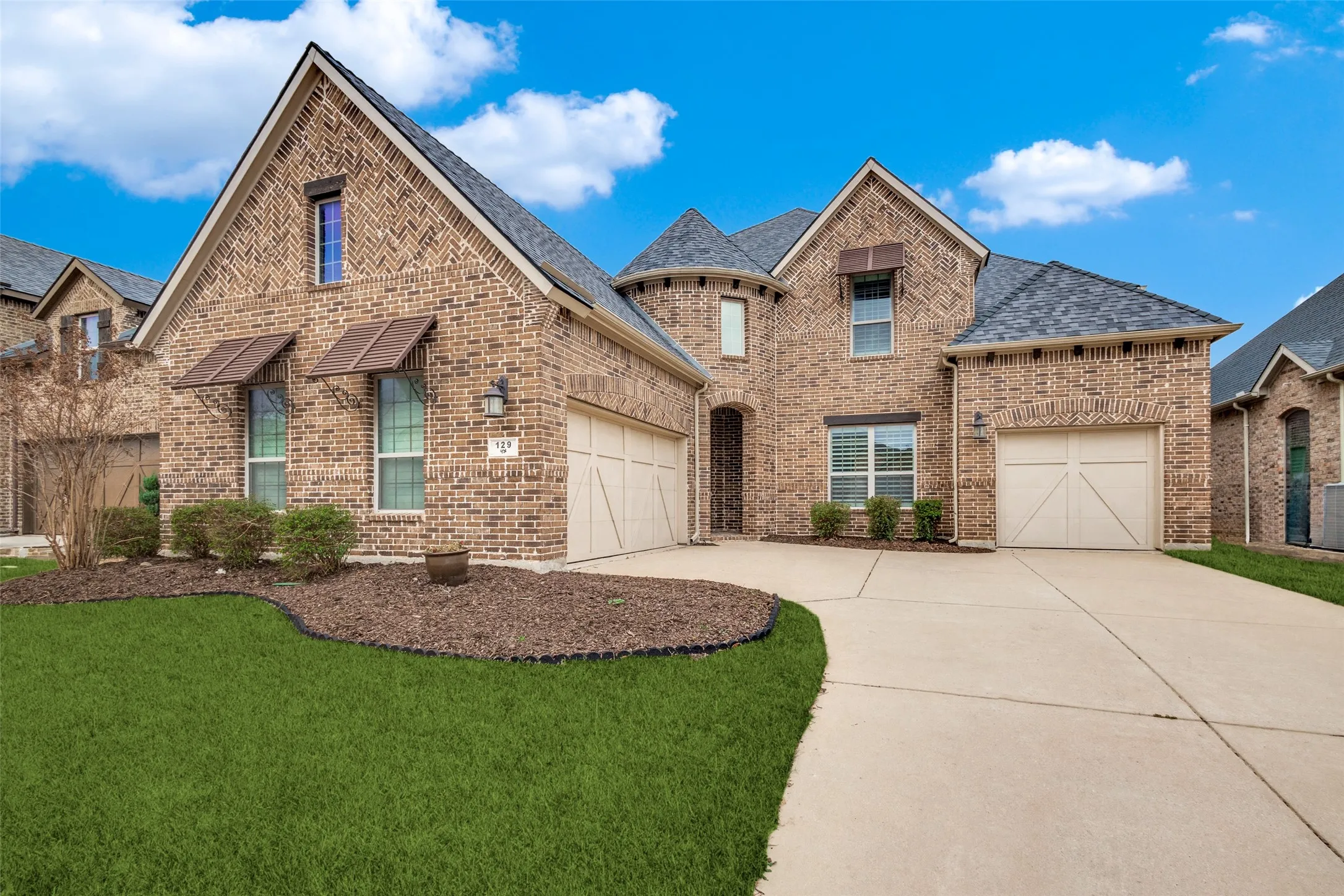 French country style house with brick siding, an attached garage, concrete driveway, and roof with shingles