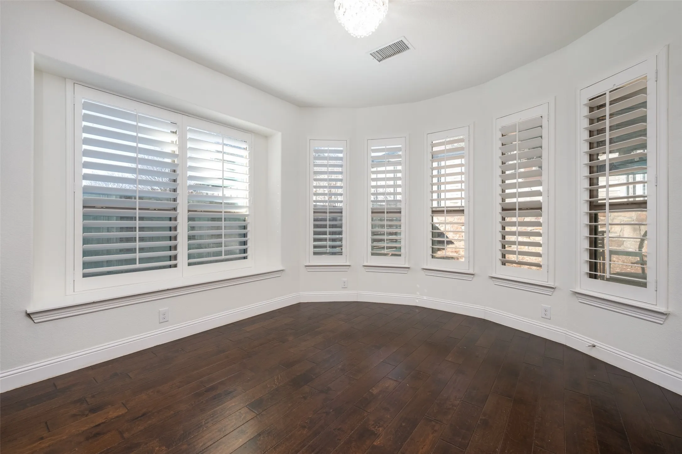 Spare room with dark wood-style flooring and baseboards