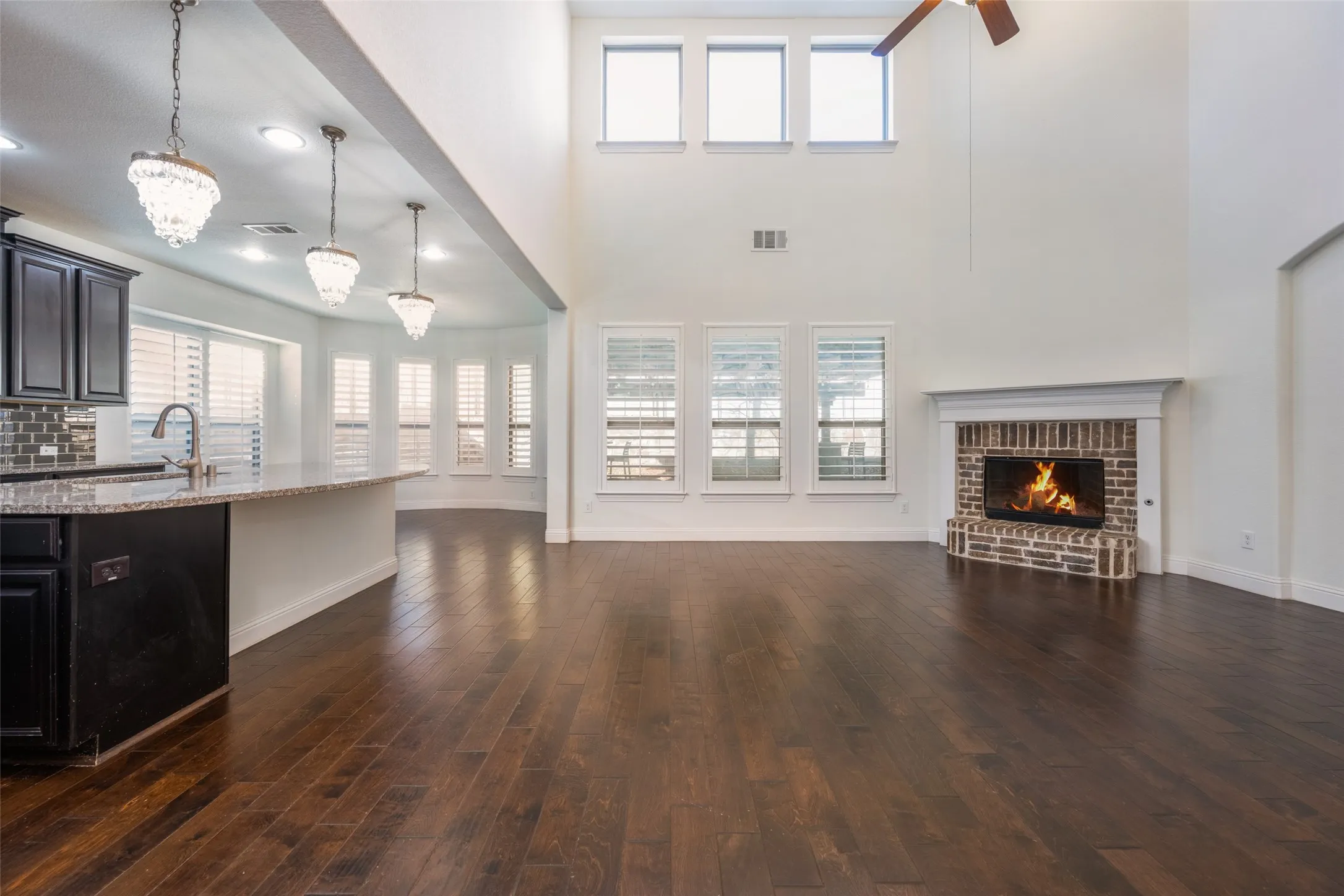 Unfurnished living room with dark wood finished floors, a fireplace, plenty of natural light, a chandelier, and a high ceiling