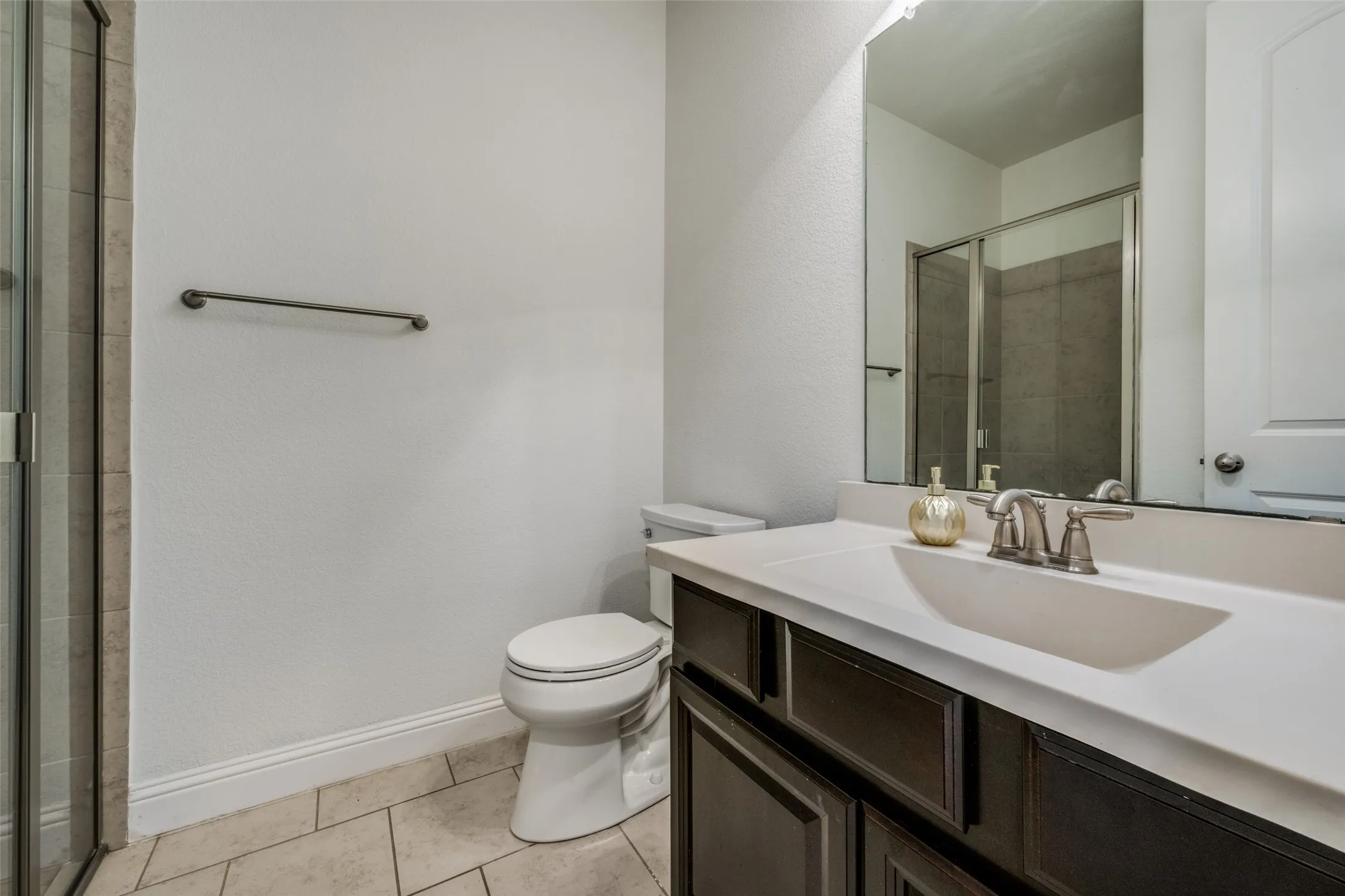 Bathroom featuring vanity, light tile patterned floors, and a tile shower