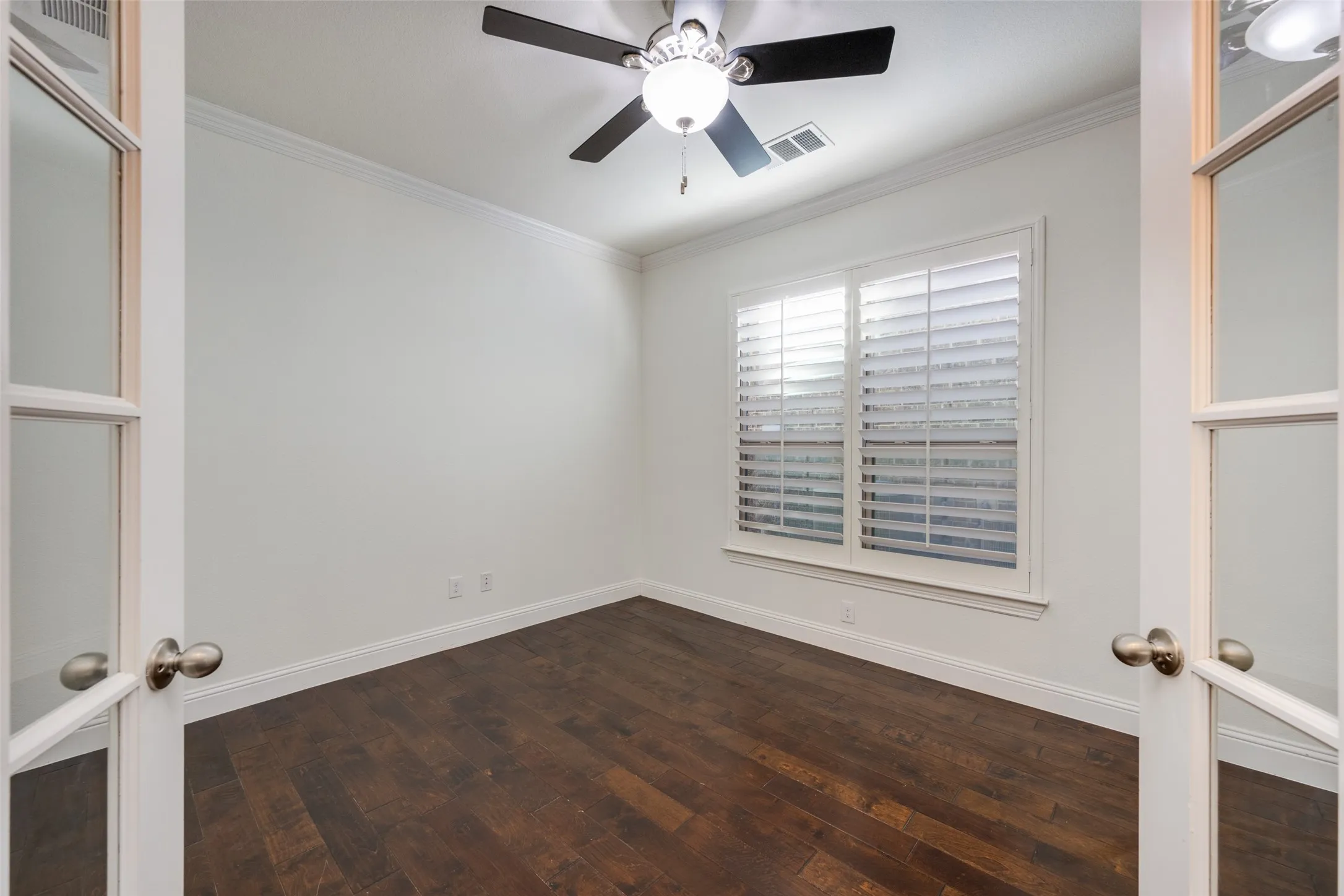Unfurnished room featuring french doors, ornamental molding, ceiling fan, and dark wood-type flooring