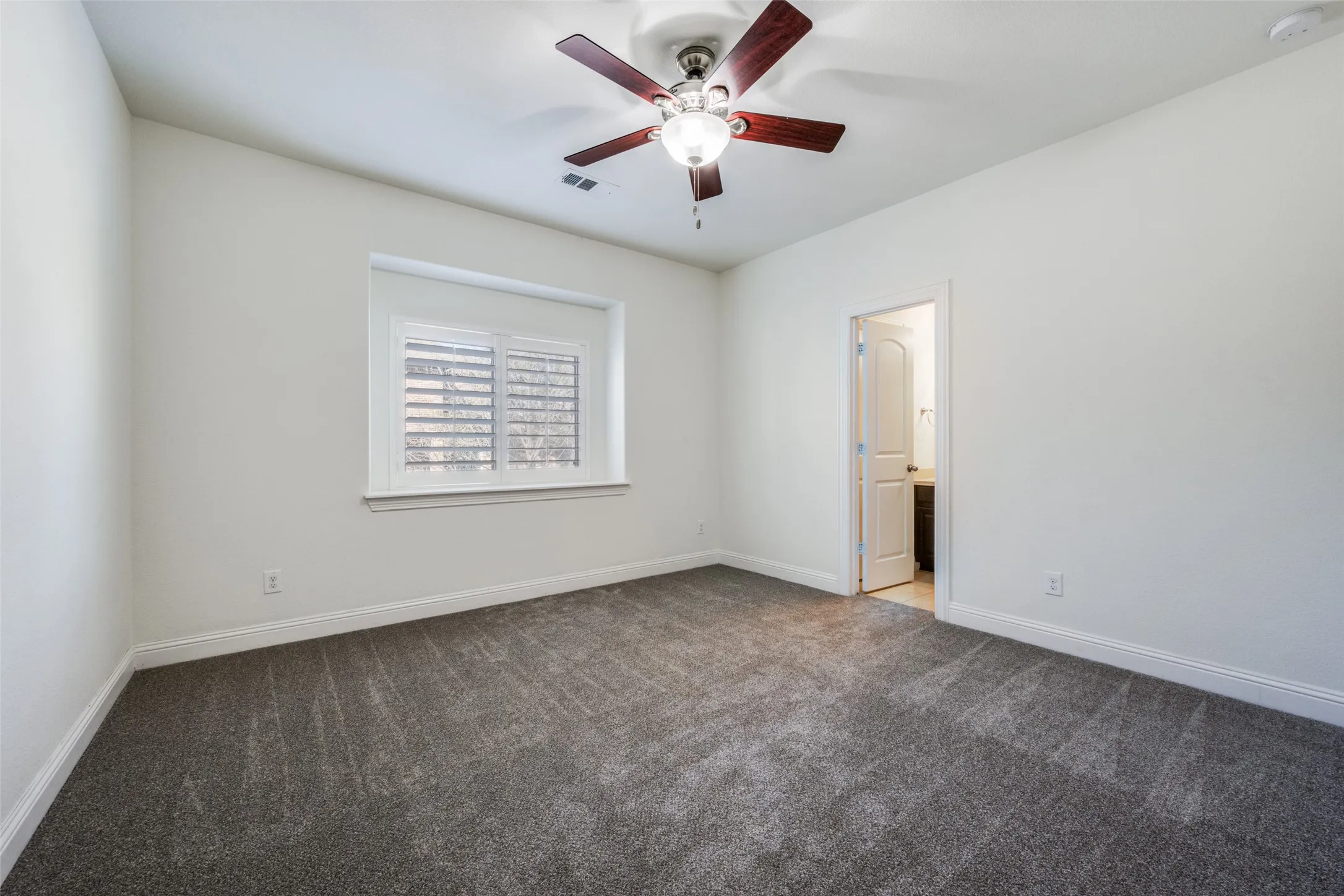 Unfurnished bedroom featuring carpet flooring, ceiling fan, and ensuite bath