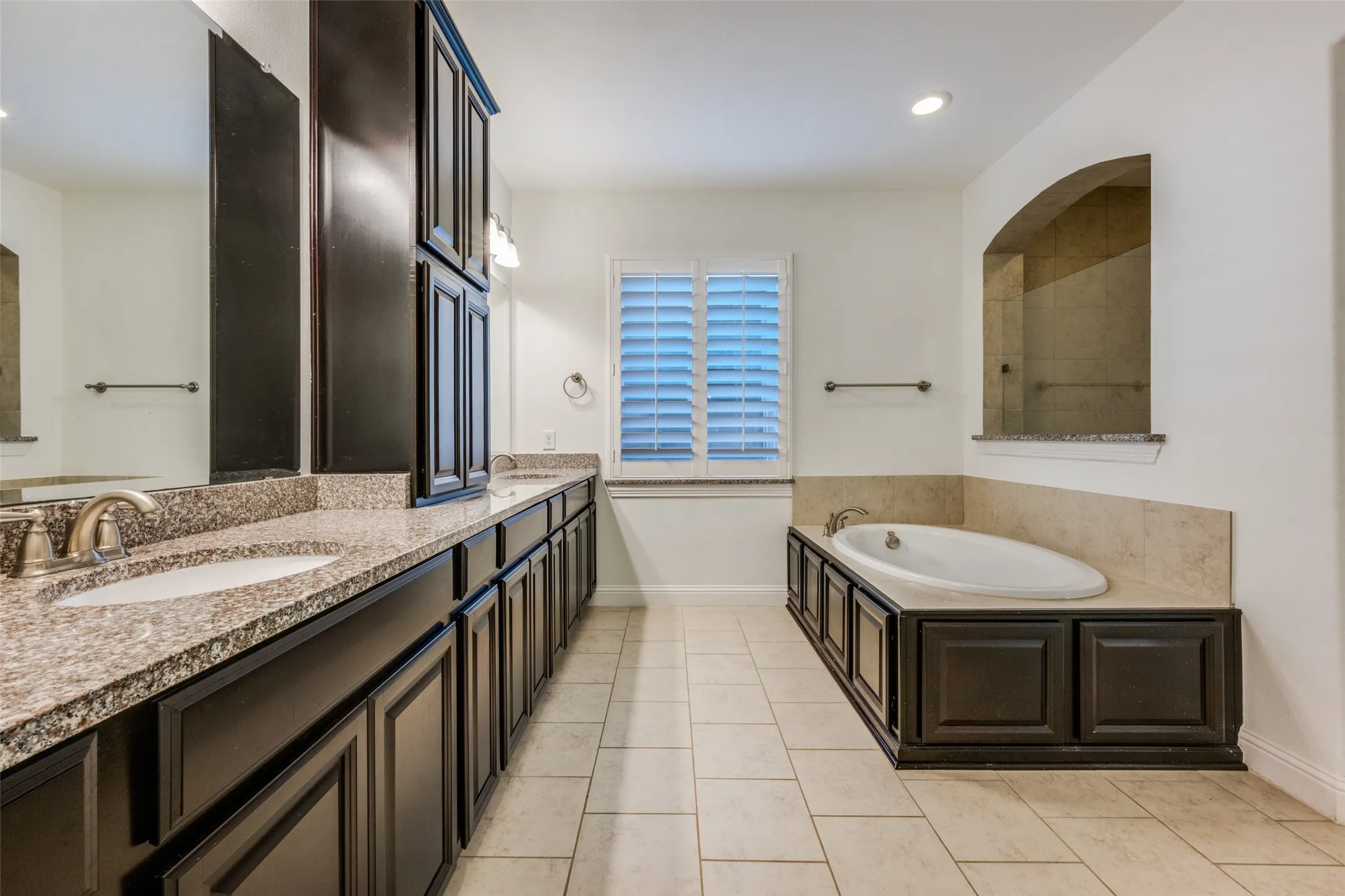 Full bath featuring double vanity, a garden tub, light tile patterned floors, and recessed lighting