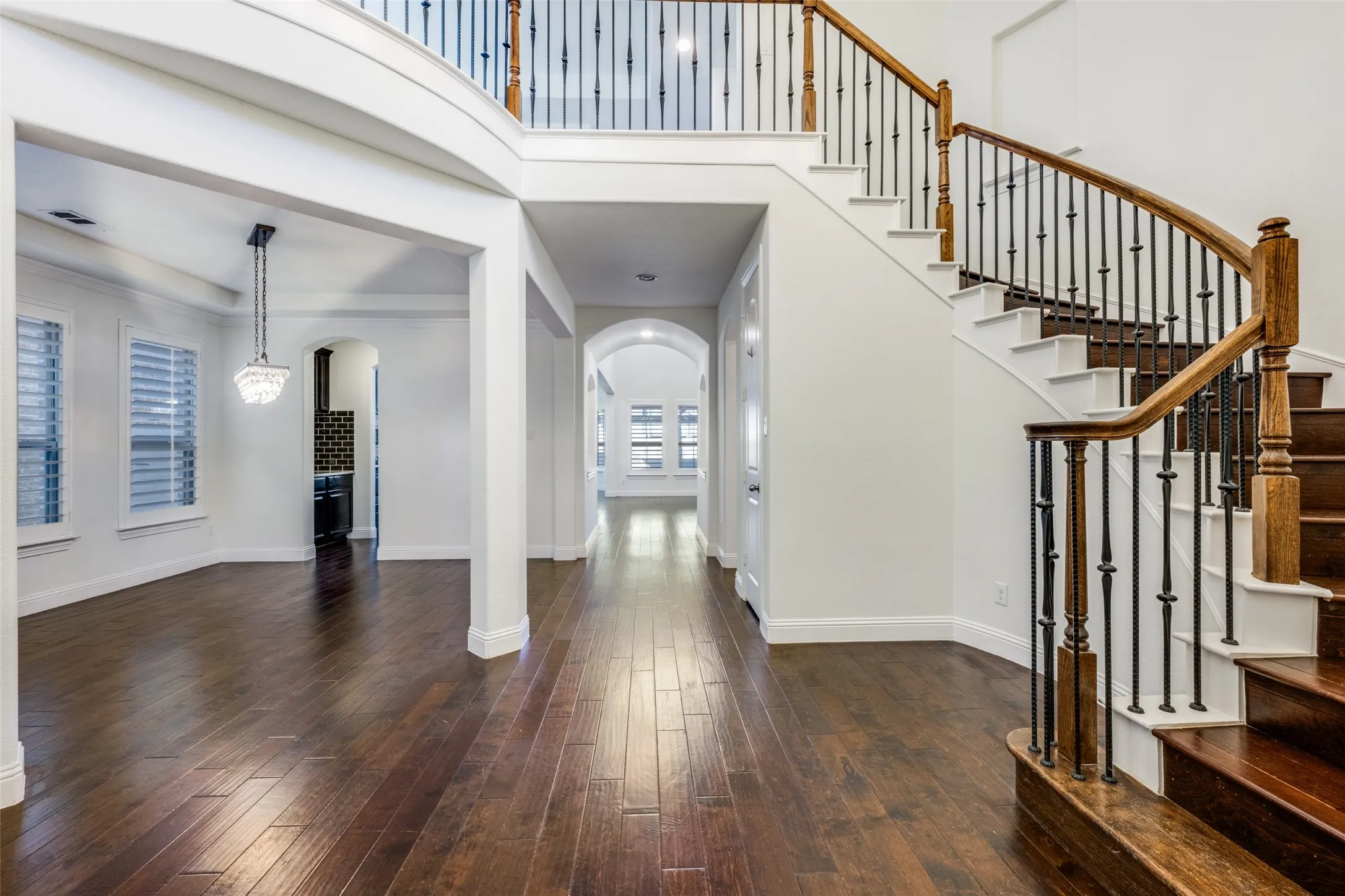 Foyer entrance featuring arched walkways, dark wood-style flooring, and a high ceiling