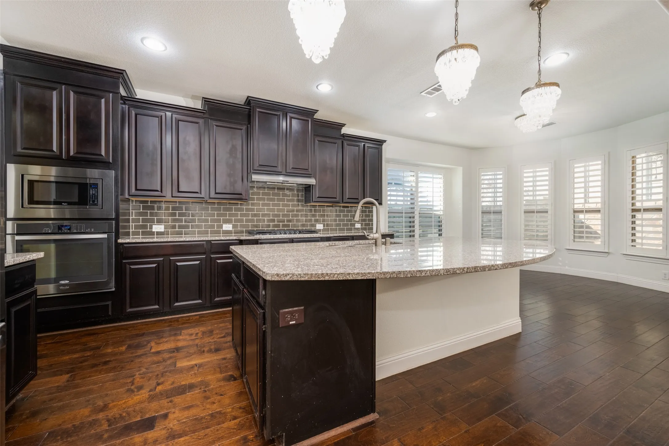 Kitchen with stainless steel appliances, light stone countertops, and dark wood finish cabinets