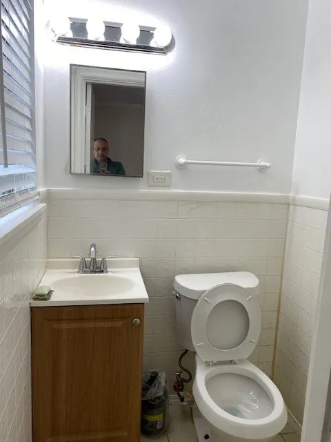 Bathroom with wainscoting, vanity, and tile walls