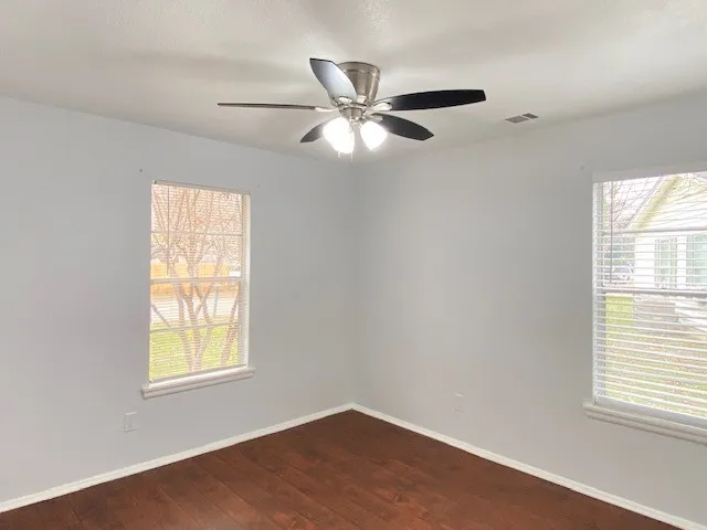 Spare room with dark wood-style flooring and a ceiling fan