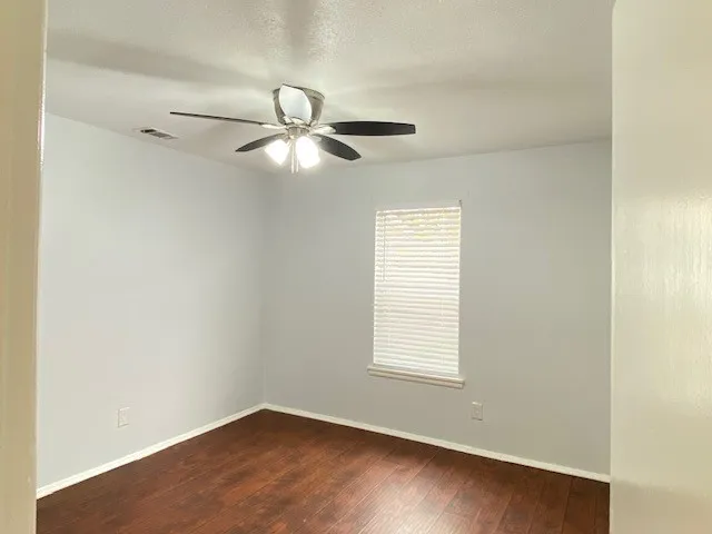 Empty room featuring dark wood finished floors, a ceiling fan, and a textured ceiling