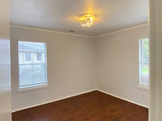 Spare room with dark wood-type flooring and ornamental molding