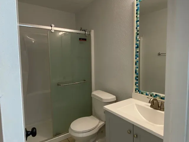 Bathroom with a textured wall, vanity, and a stall shower
