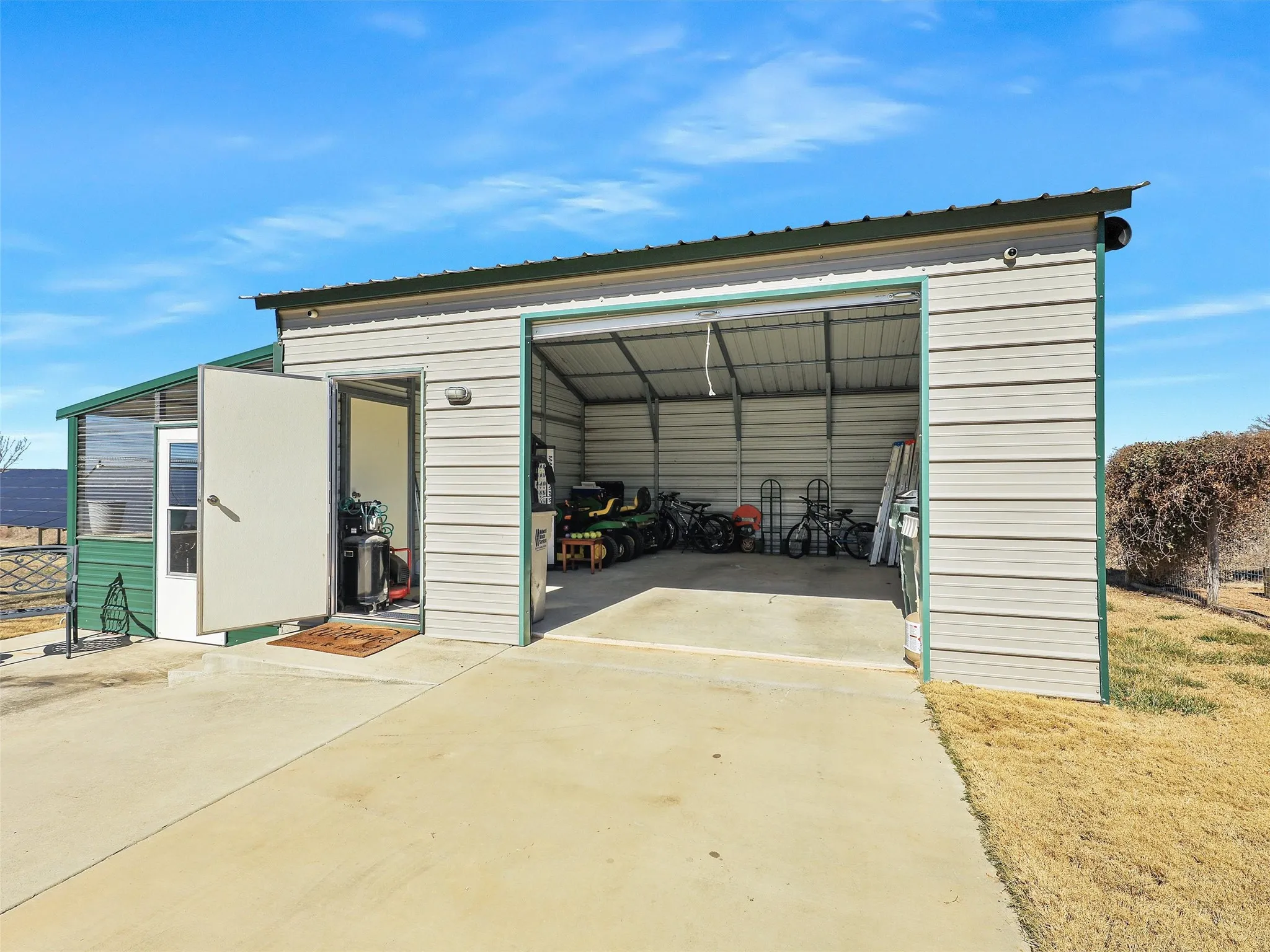 Greenhouse with Single Metal Garage Combo with Concrete Driveway Access.