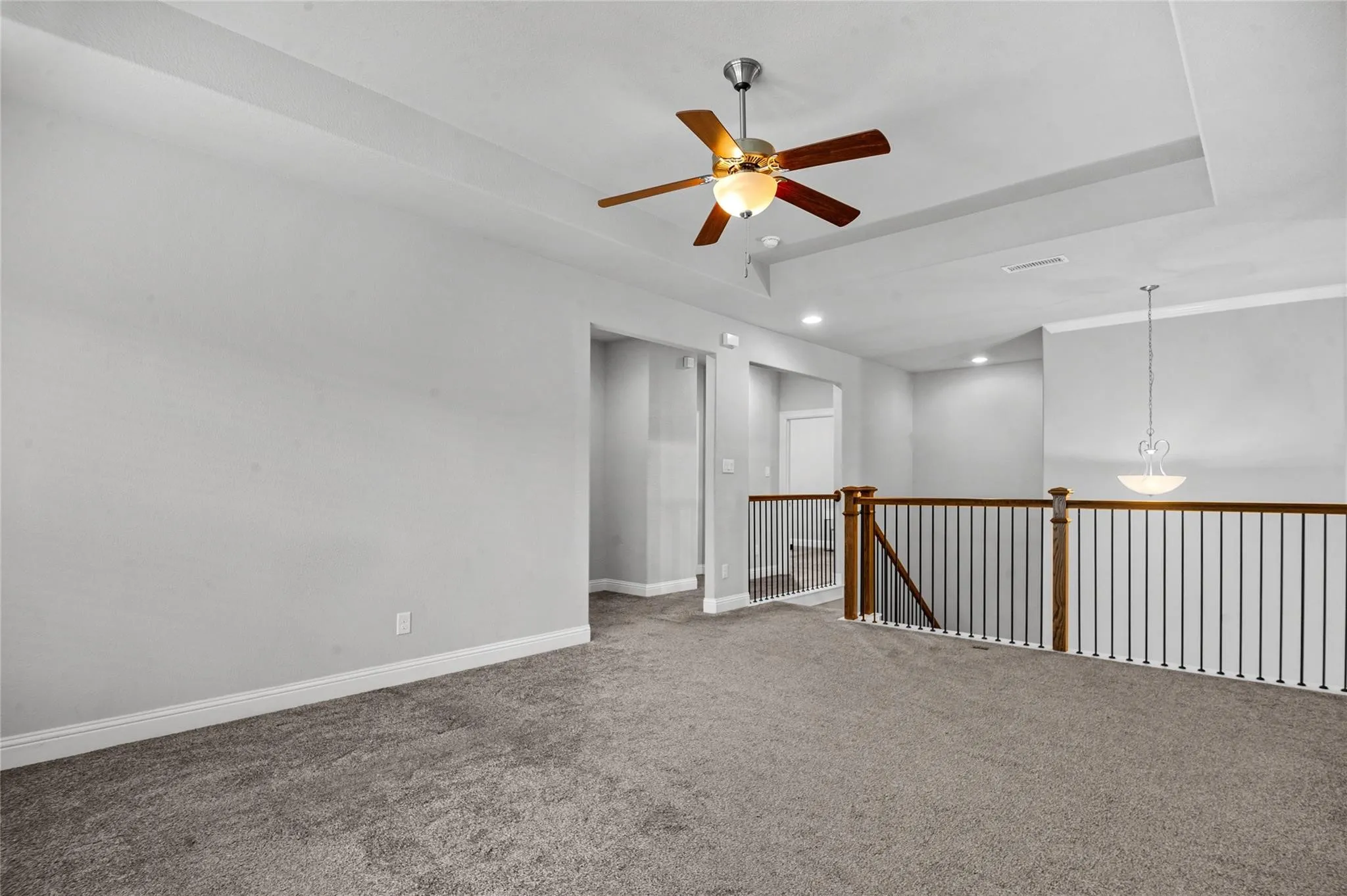 Empty room with carpet floors, a raised ceiling, and ceiling fan
