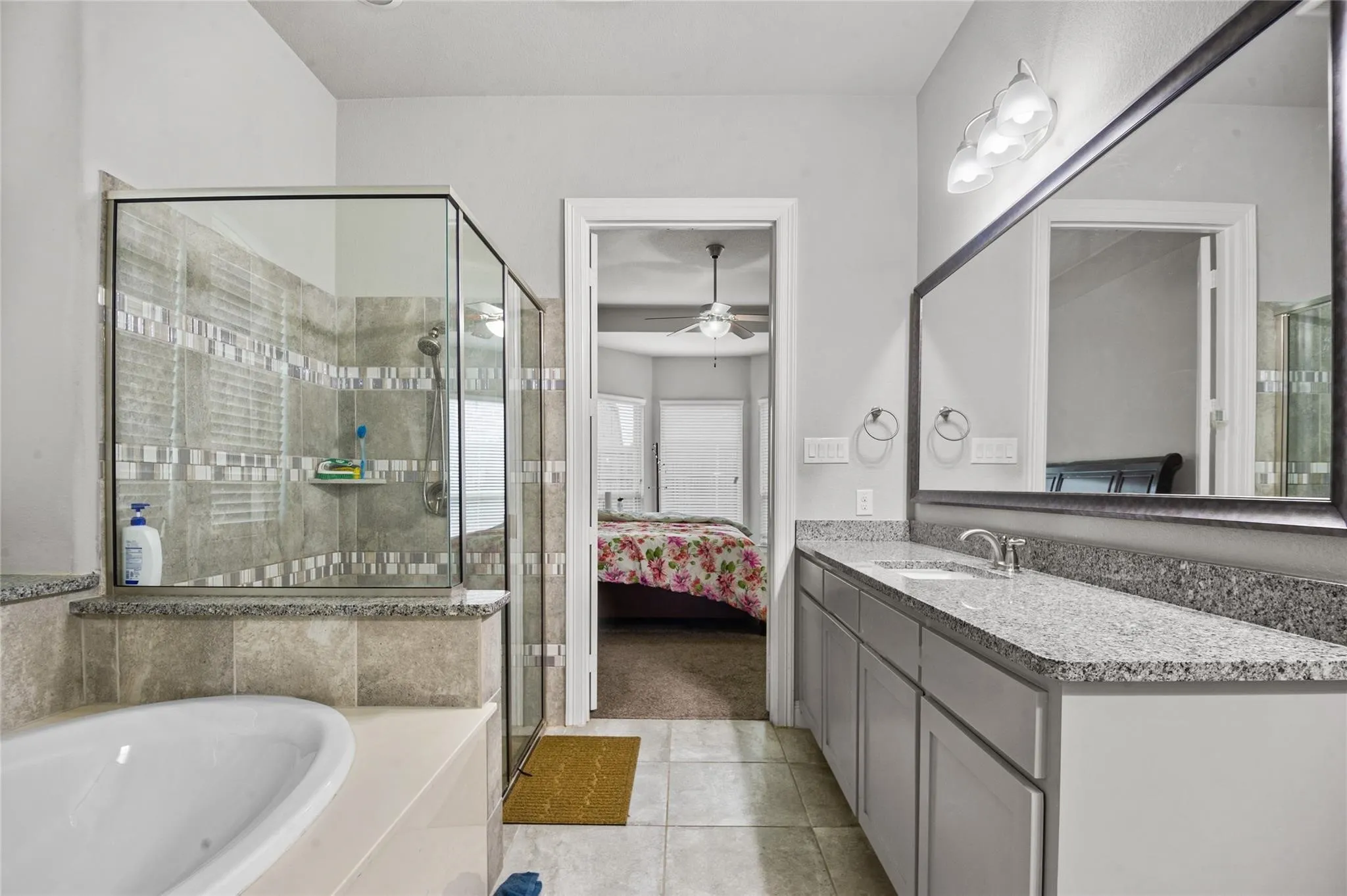 Full bathroom featuring ensuite bathroom, vanity, a shower stall, light tile patterned flooring, and a bath