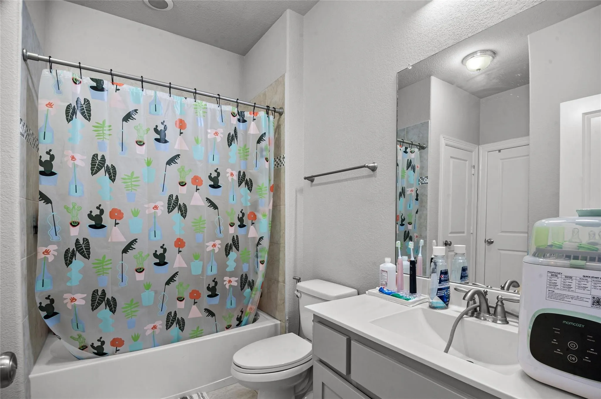 Bathroom featuring vanity, shower / bath combo with shower curtain, a textured wall, and a textured ceiling