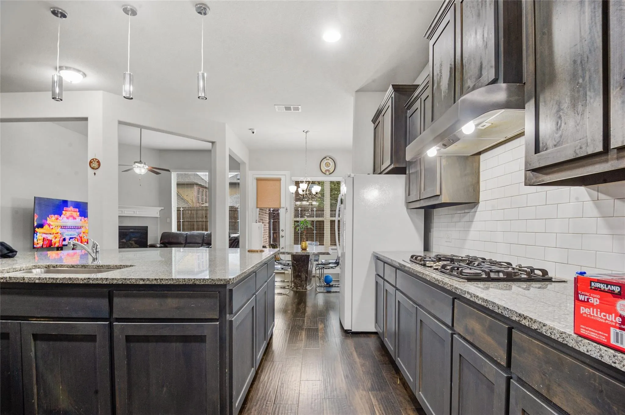 Kitchen with a fireplace, light stone counters, dark wood finish cabinets, and dark wood-style flooring