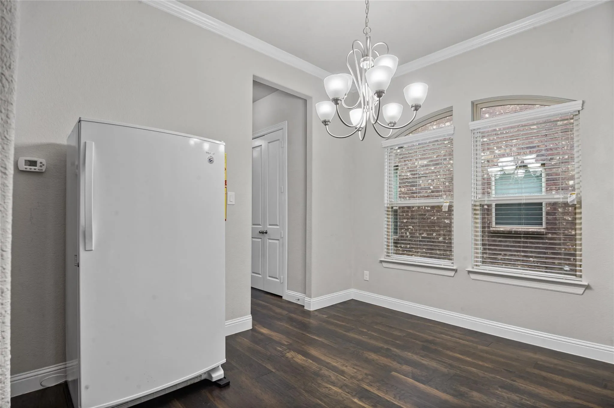 Unfurnished dining area featuring a chandelier, dark wood-type flooring, and ornamental molding