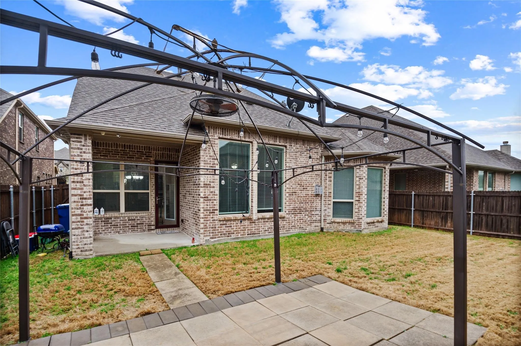 Rear view of house with a patio area, brick siding, a shingled roof, and a fenced backyard