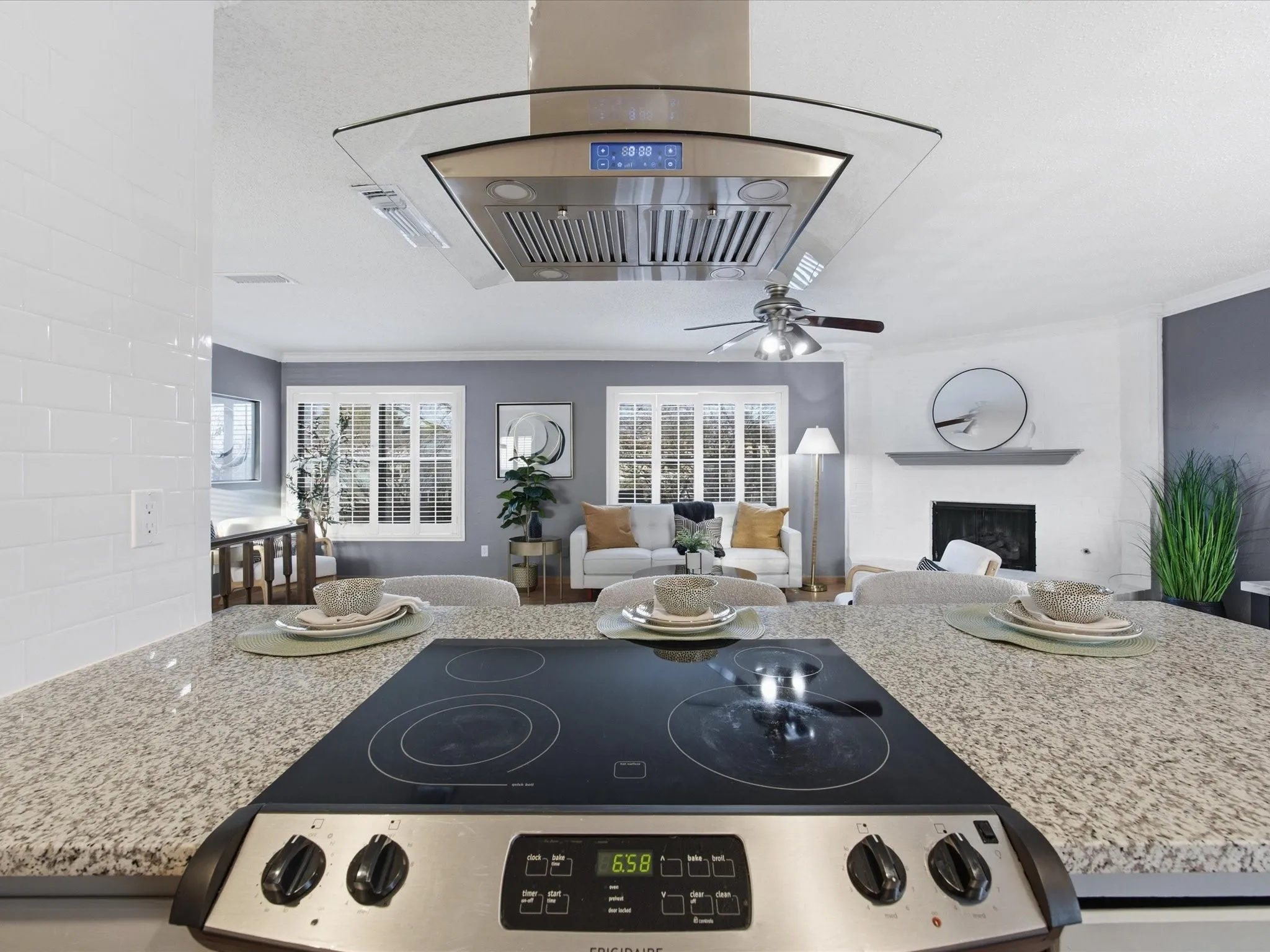 Kitchen with a breakfast bar area, tasteful backsplash, island range hood, a peninsula, and black appliances